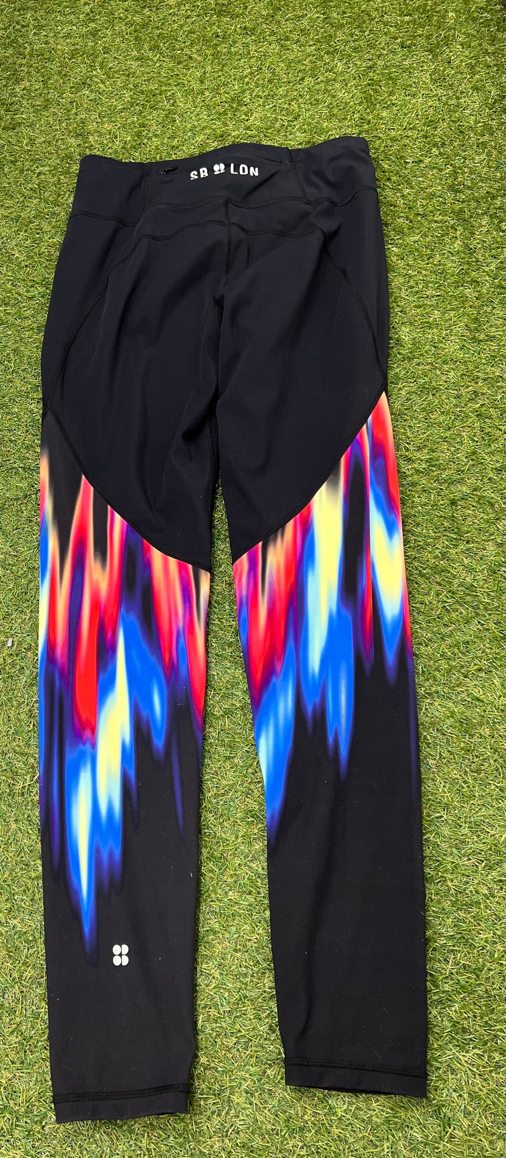 Back view of black gym leggings showcasing the colourful abstract print on the calf area and small logo near ankle
