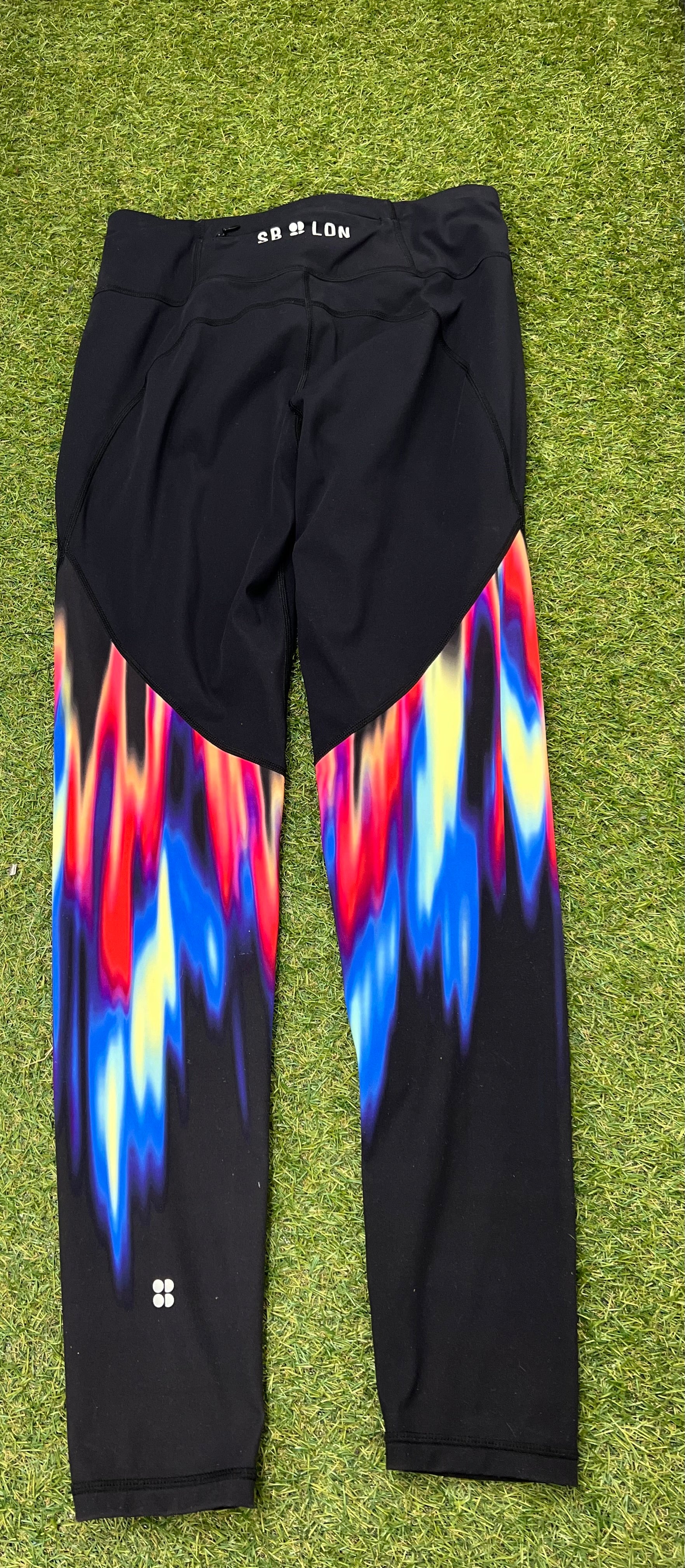 Back view of black gym leggings showcasing the colourful abstract print on the calf area and small logo near ankle