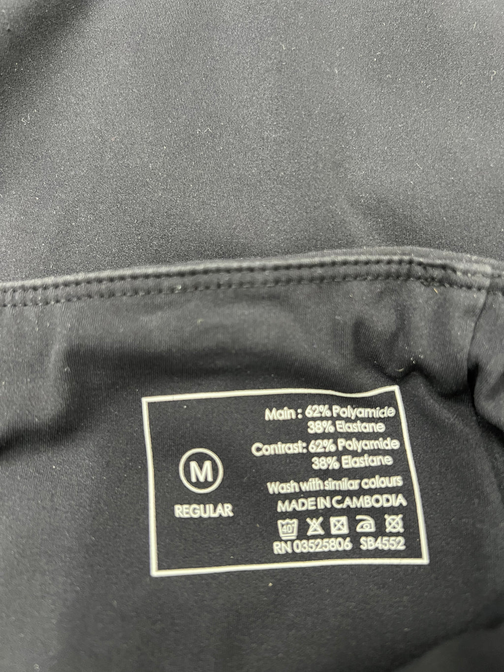 Close-up image of fabric care label showing material composition as 62% polyamide and 38% elastane with washing instructions