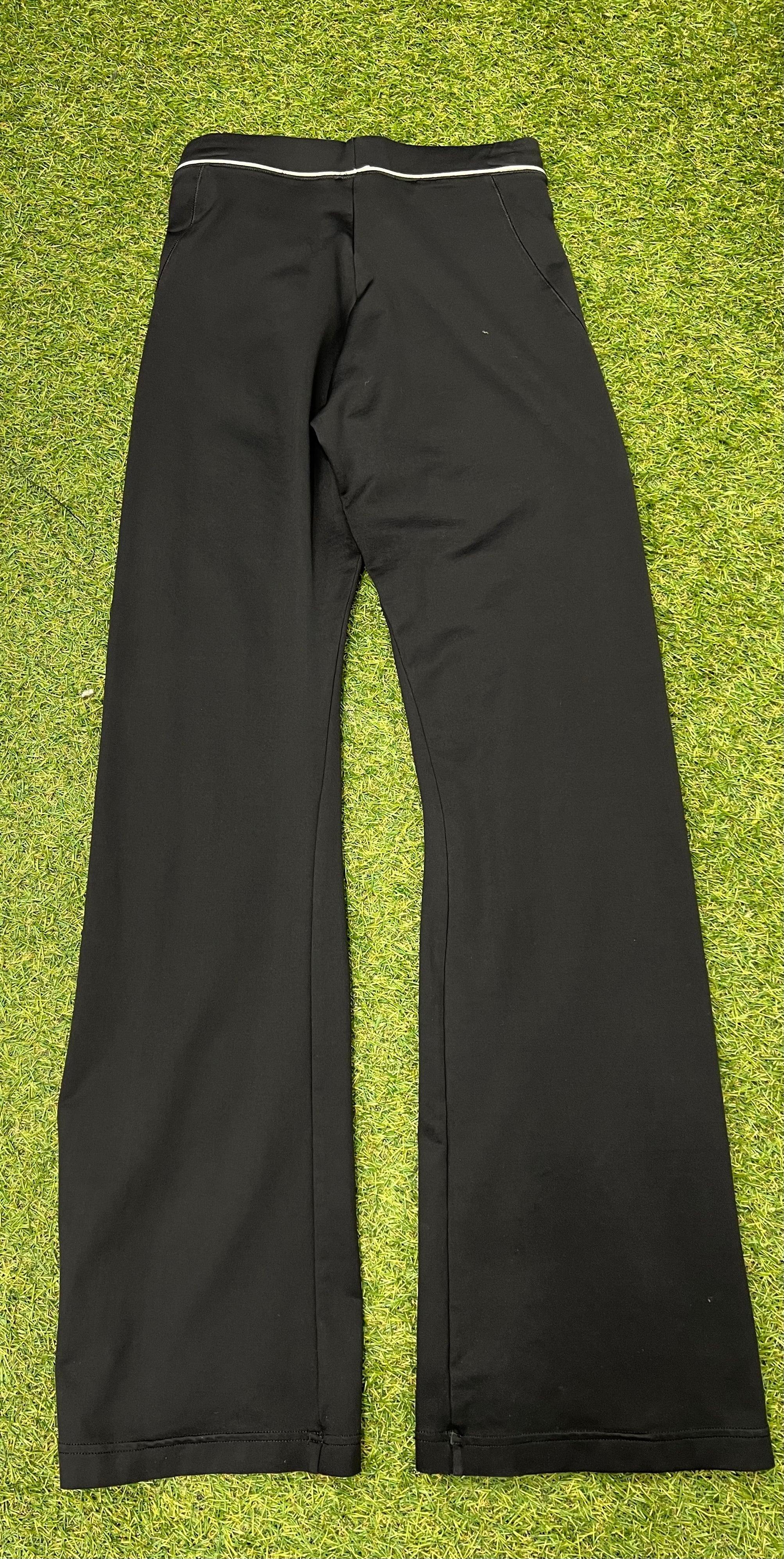 Back view of Adidas black yoga pants showing plain design and waistband detail on green turf