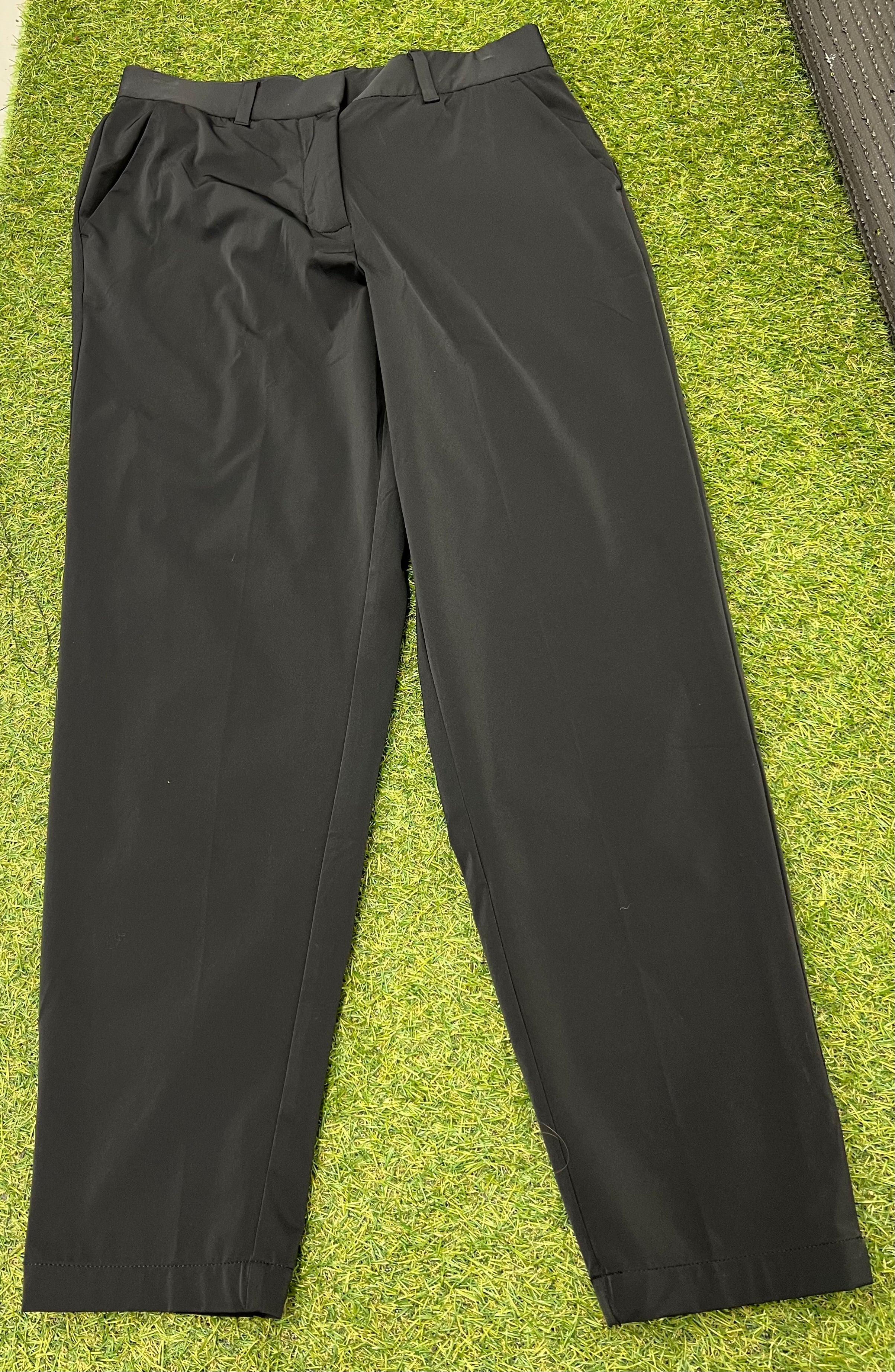 Front view of black Nike women's sports trousers laid flat on grass