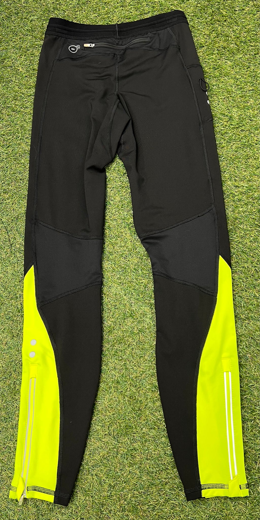 Back view of black Puma leggings showing zippered pocket, reflective strips and yellow panels on calves