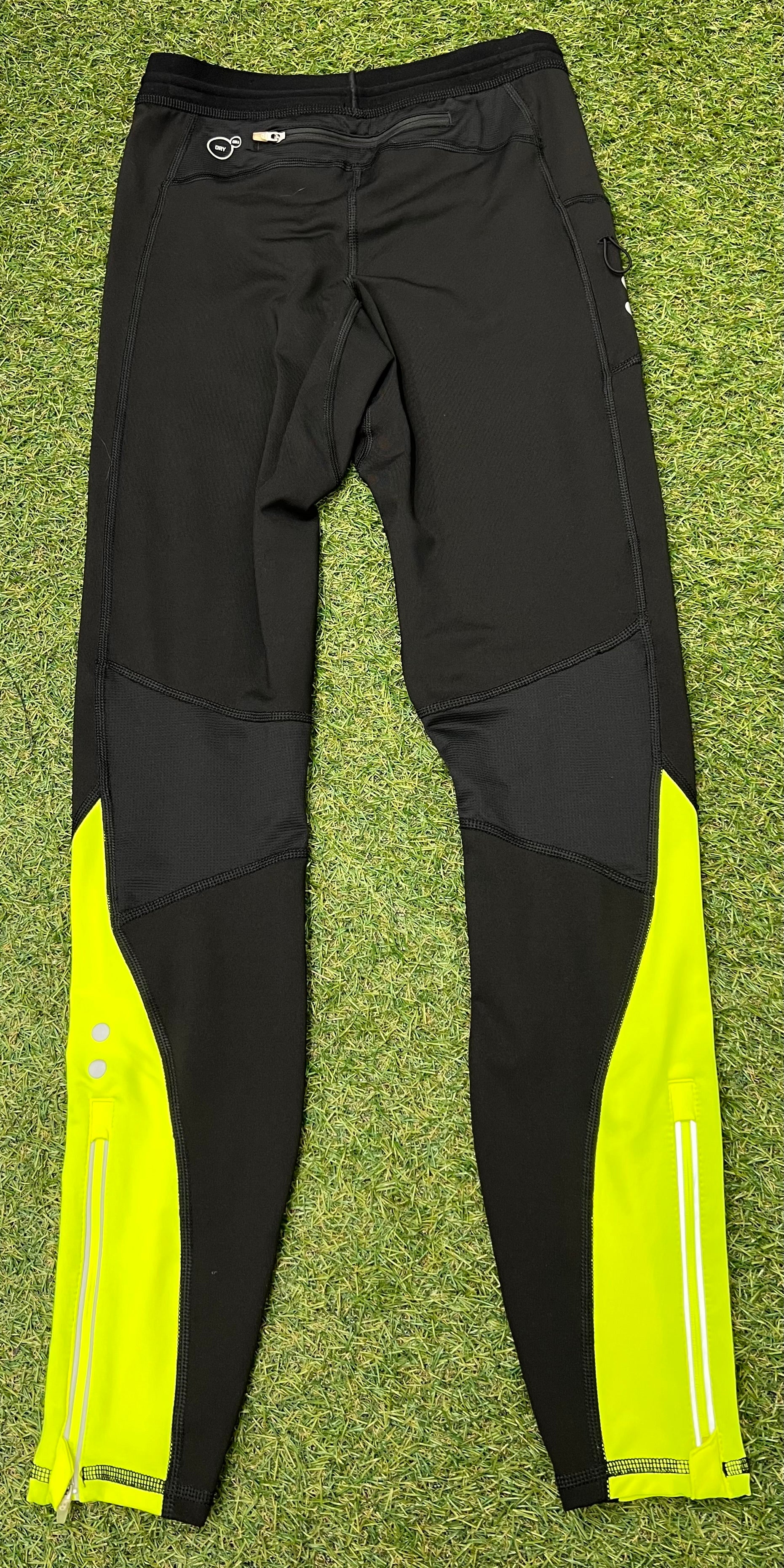 Back view of black Puma leggings showing zippered pocket, reflective strips and yellow panels on calves