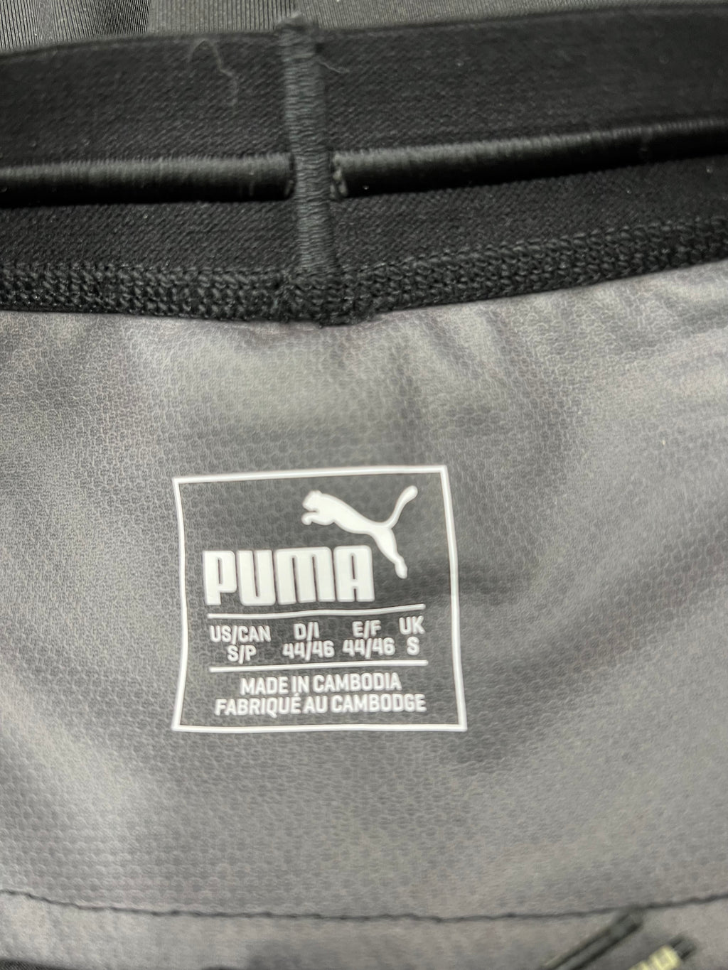 Close-up of inner waistband label showing Puma logo and size details on black leggings