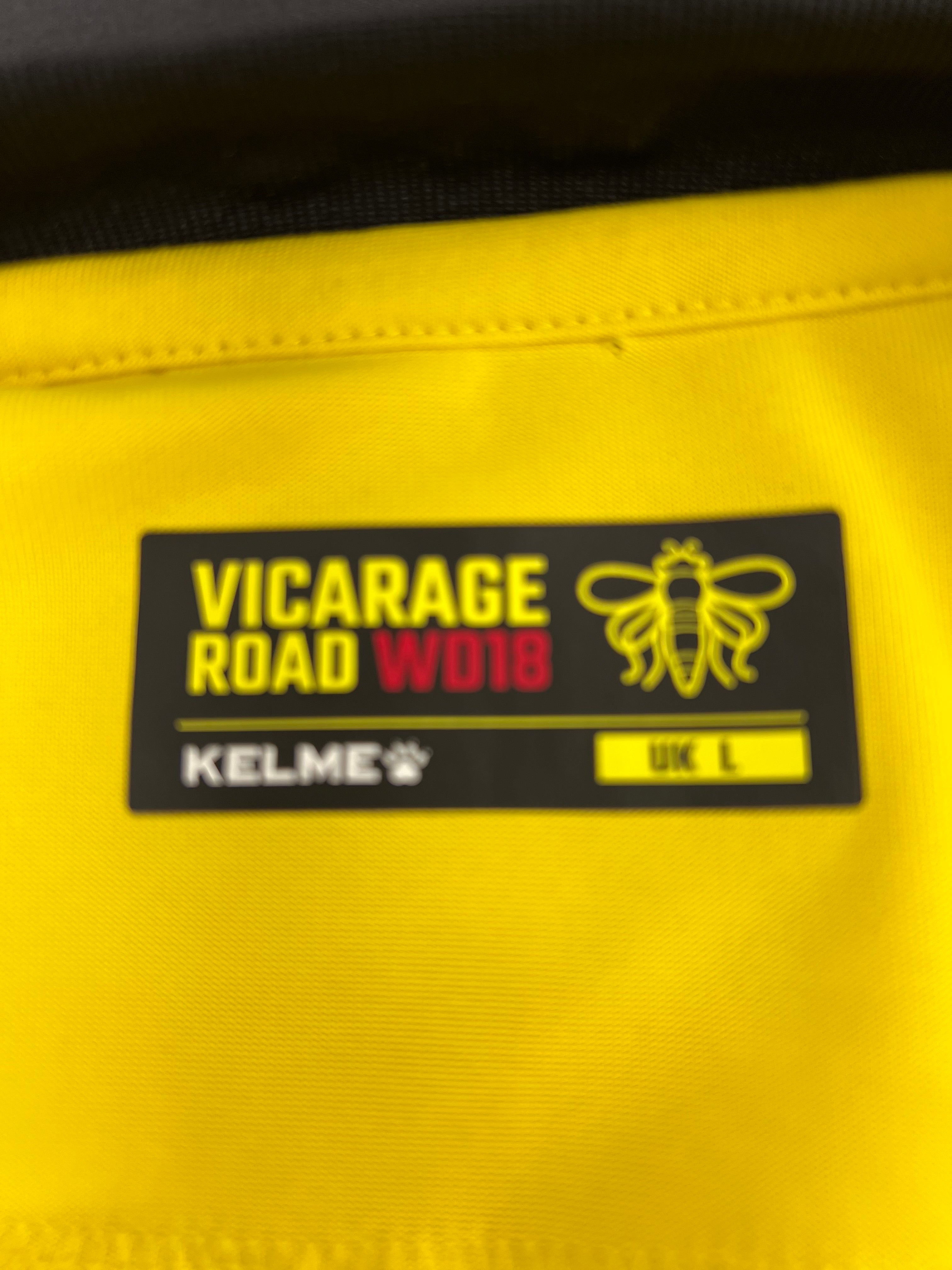 Label inside the shirt showing Vicarage Road address, Kelme branding, and size UK L on yellow fabric