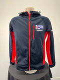 Front view of navy blue Musto British Sailing Team softshell jacket with red side panels and chest zipper pocket