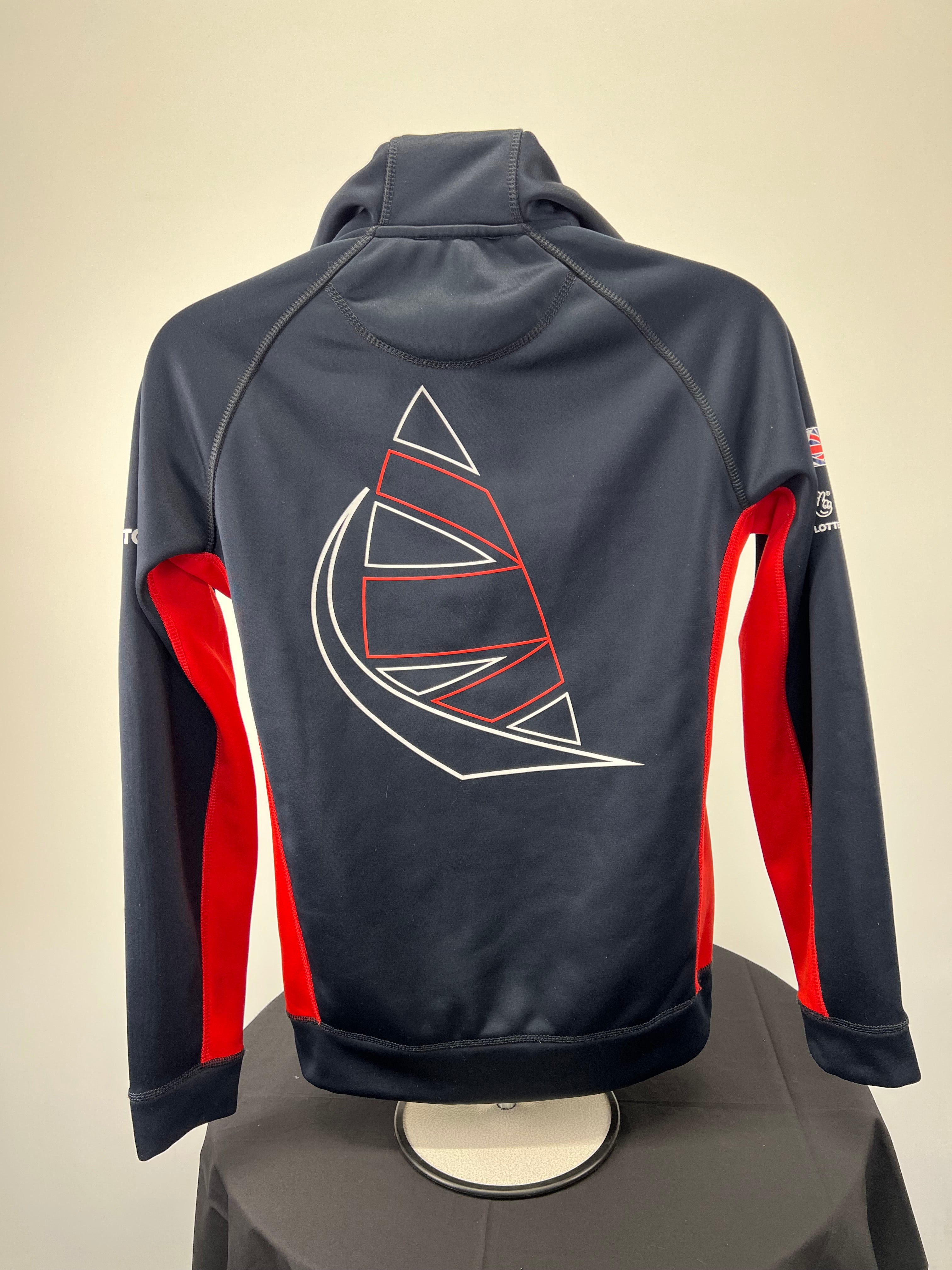 Back view of navy Musto jacket showing large red and white abstract sail design and red side accents