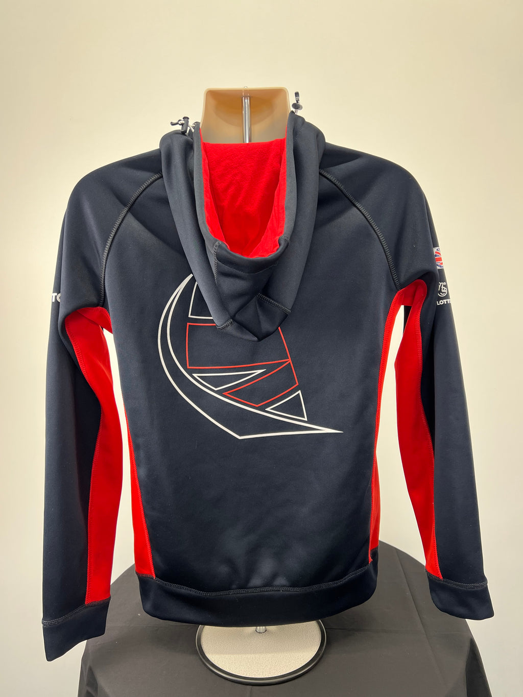 Alternate angle view of navy Musto sailing jacket with red fleece-lined hood and sleeves