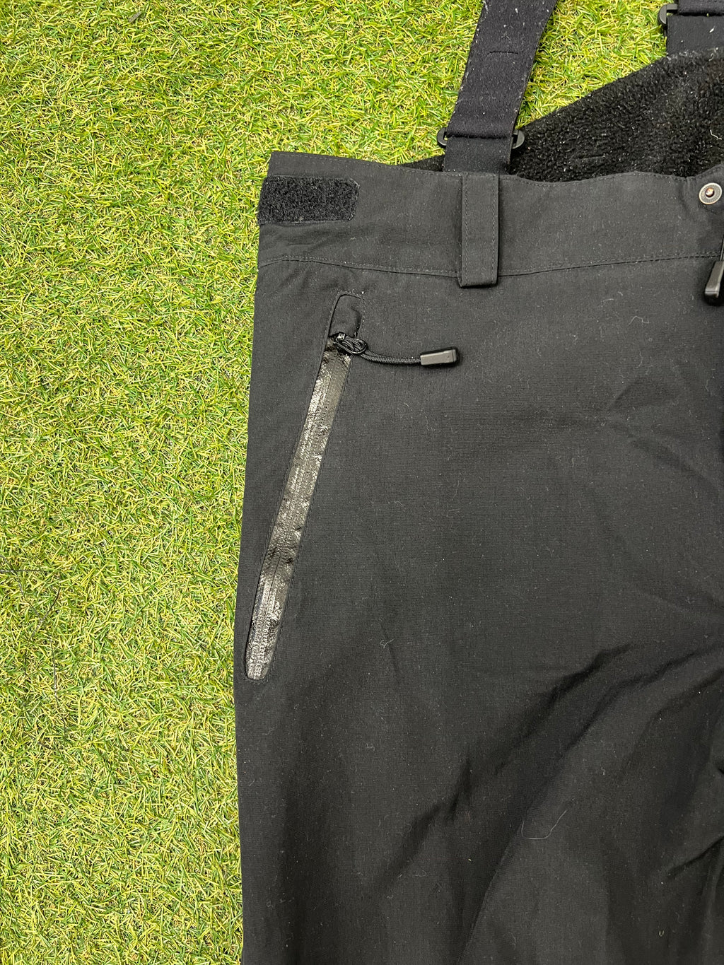 Close-up of front left zipped pocket with waterproof tape on black Eider ski trousers