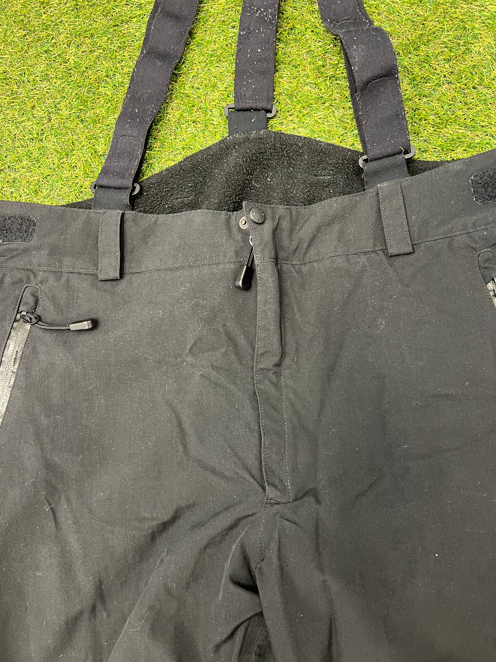 Upper front view showing adjustable braces and waistband of black Eider ski trousers