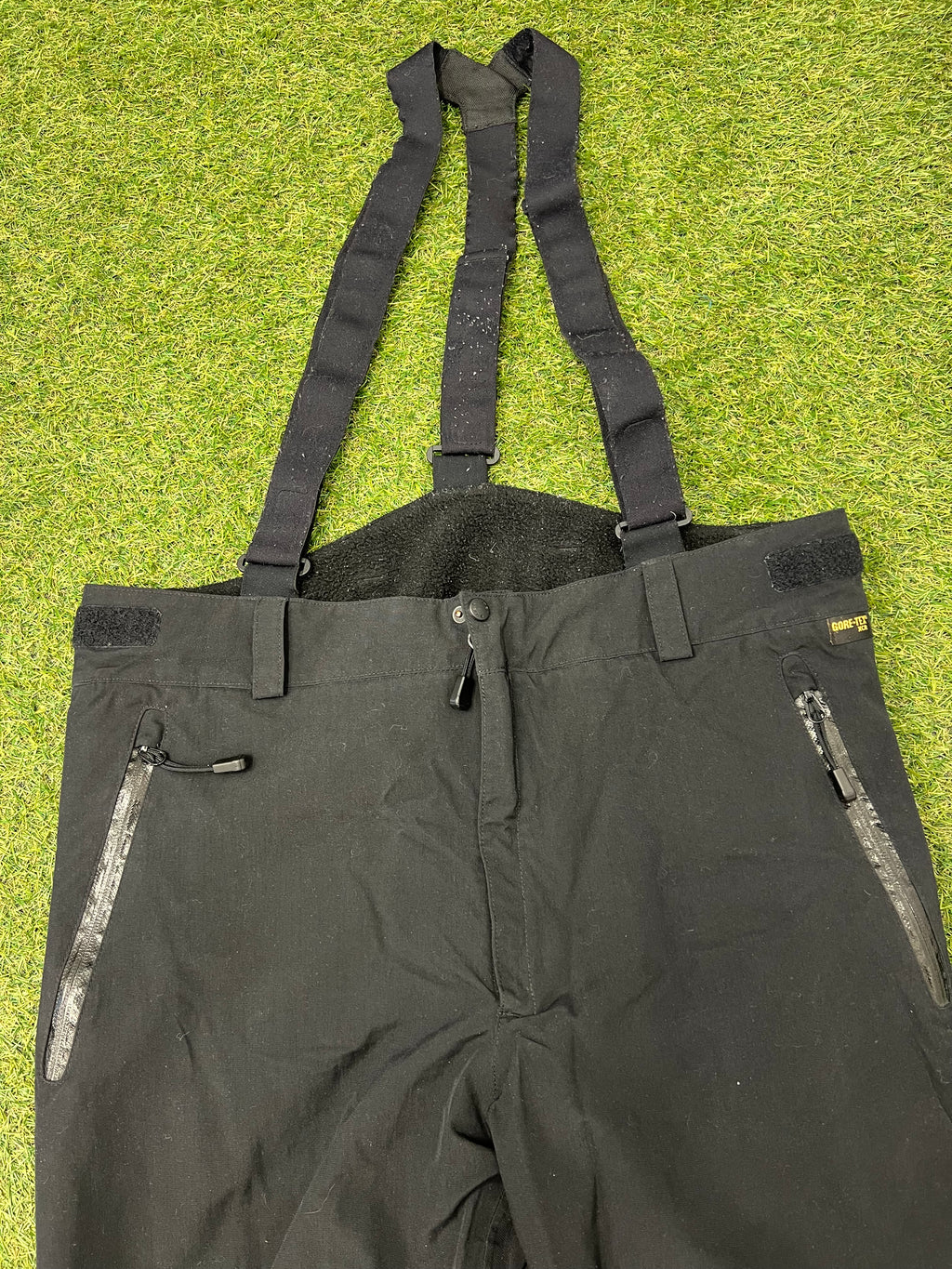 Close-up detail of Gore-Tex tag and zipped pocket on black ski trousers