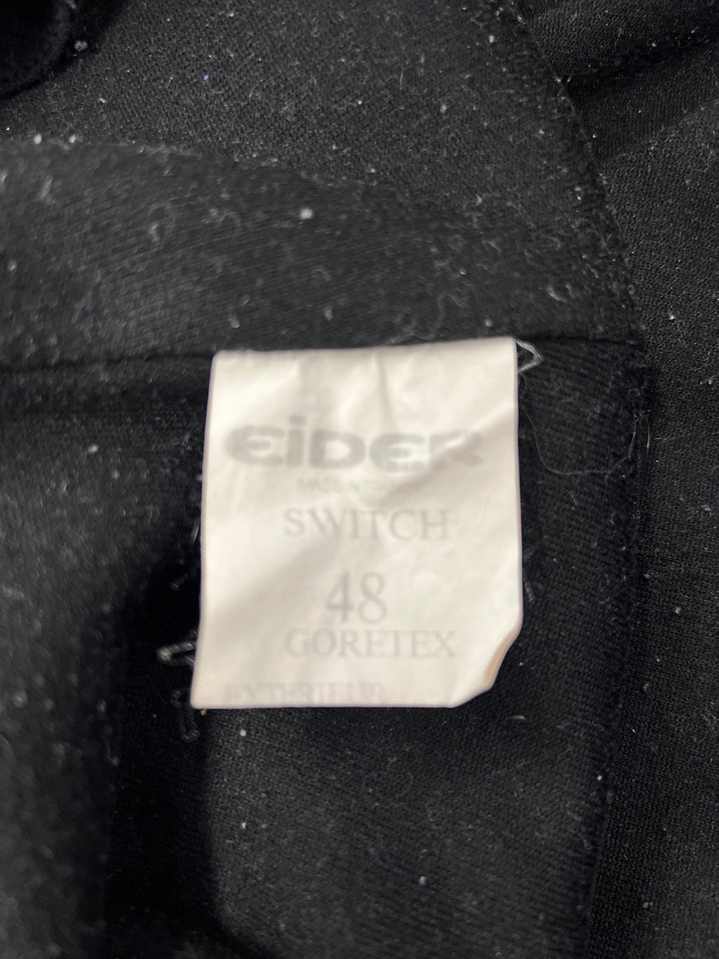 Close-up of front zipper and snap button fly closure on black Eider ski trousers
