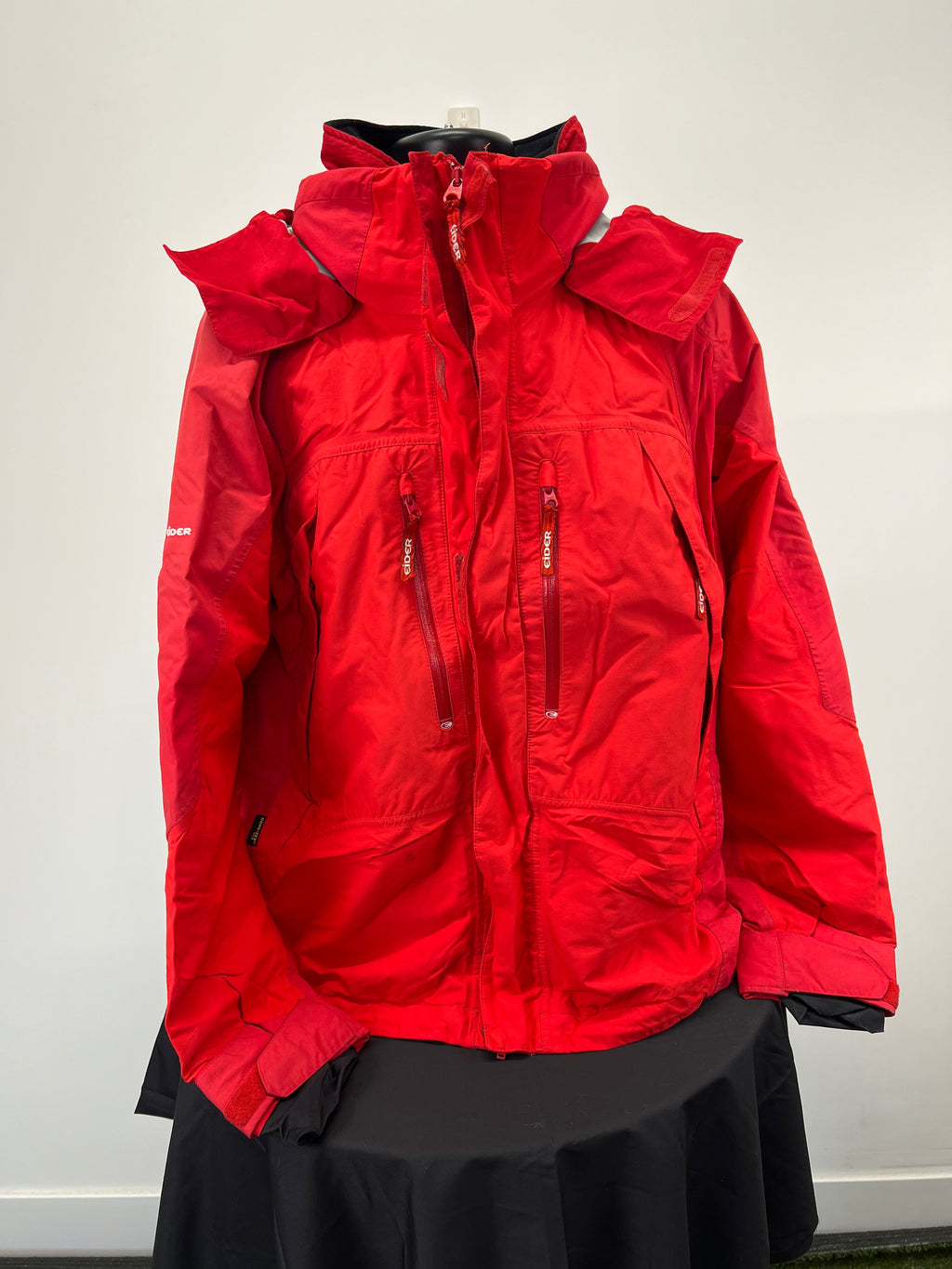 Front view of red Eider men's ski jacket with zippered pockets and adjustable cuffs on mannequin