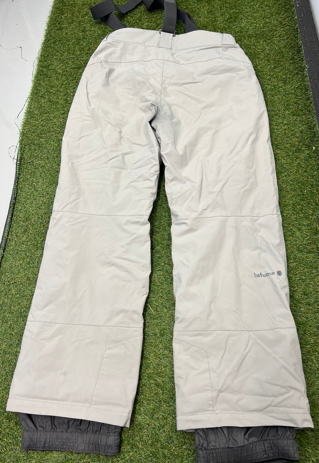 Rear view of light grey Lafuma ski trousers showing reinforced knees and elasticated inner cuffs on grass