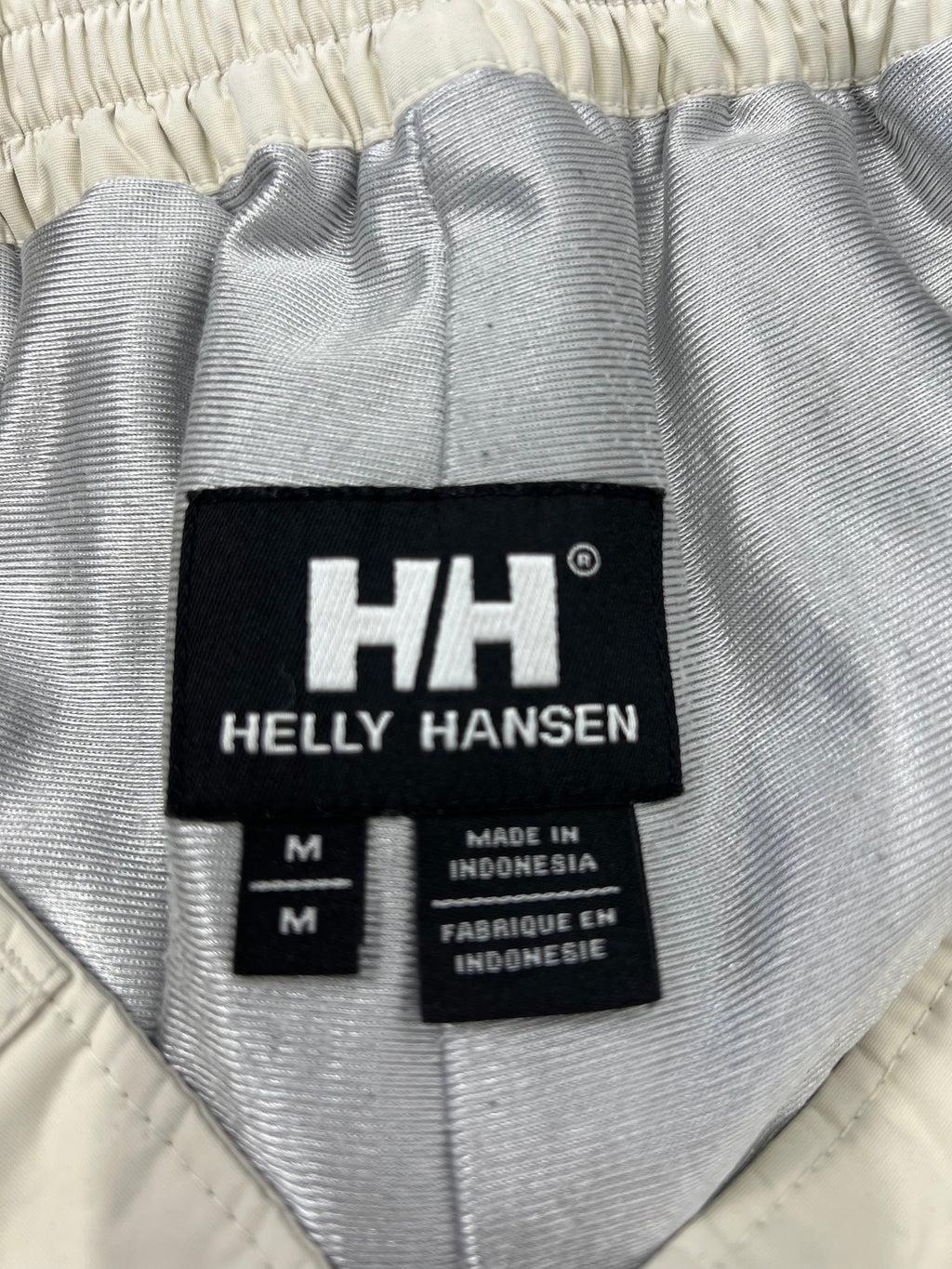 Close-up of Helly Hansen brand label inside the waistband of cream ski trousers showing medium size and Made in Indonesia tag