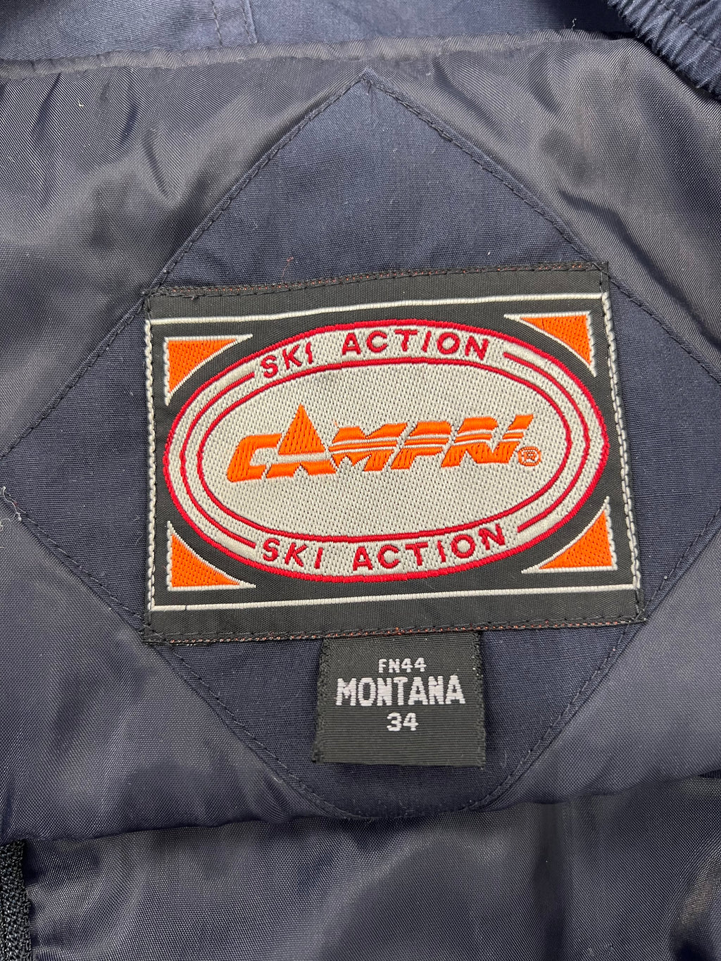 Close-up of Campri Ski Action brand label and Montana size 34 tag inside the black salopettes