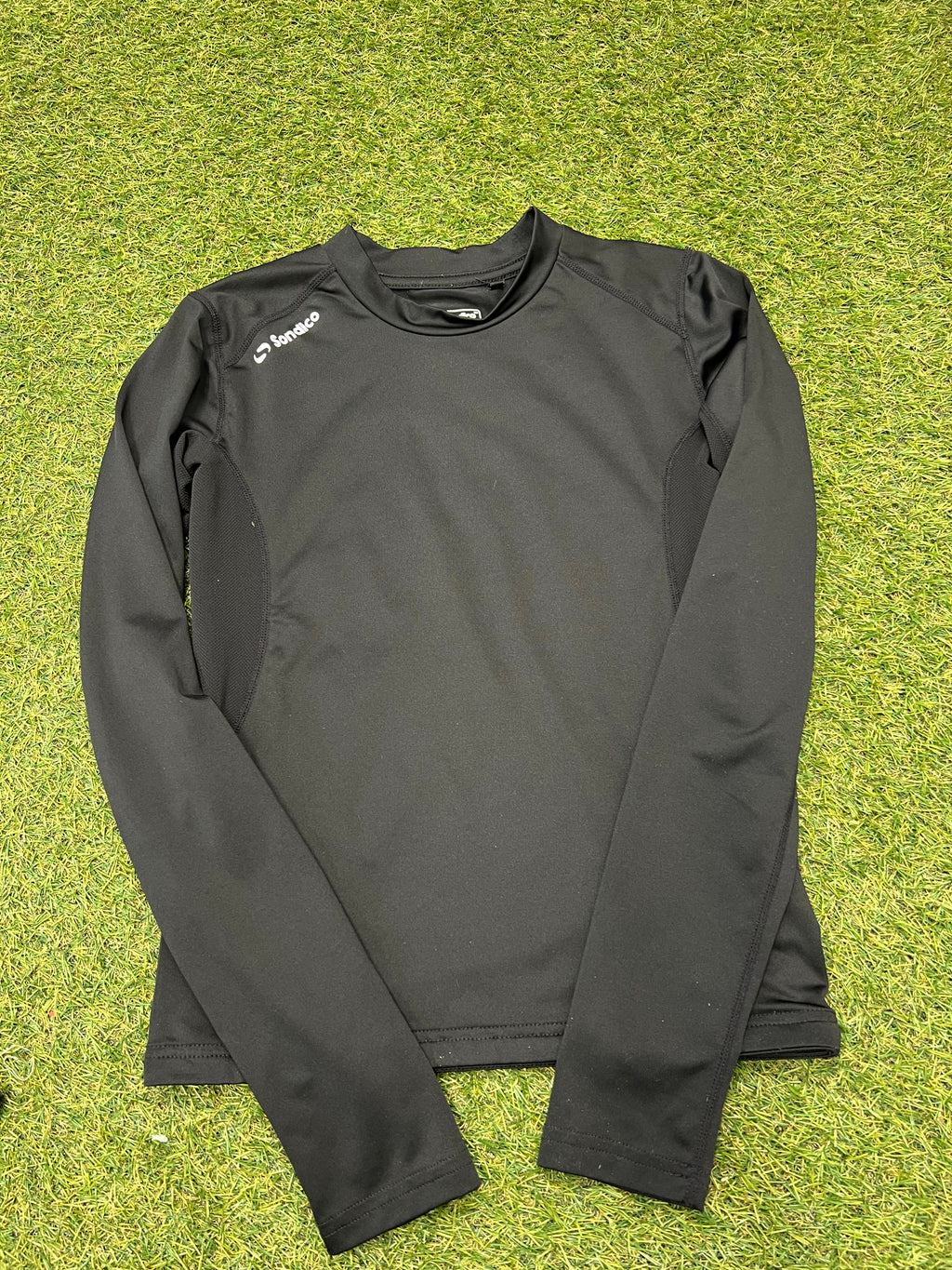 Close-up front view of black Sondico kids long sleeve top with subtle branding on chest and shoulder