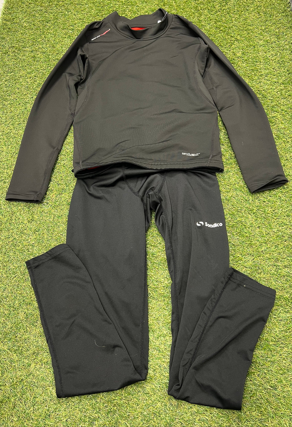 Sondico black kids base layer top and leggings laid flat on green artificial grass.
