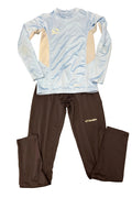 Sondico kids base layer set laid out on grass showing a sky blue long-sleeve top with beige mesh side panels and black leggings