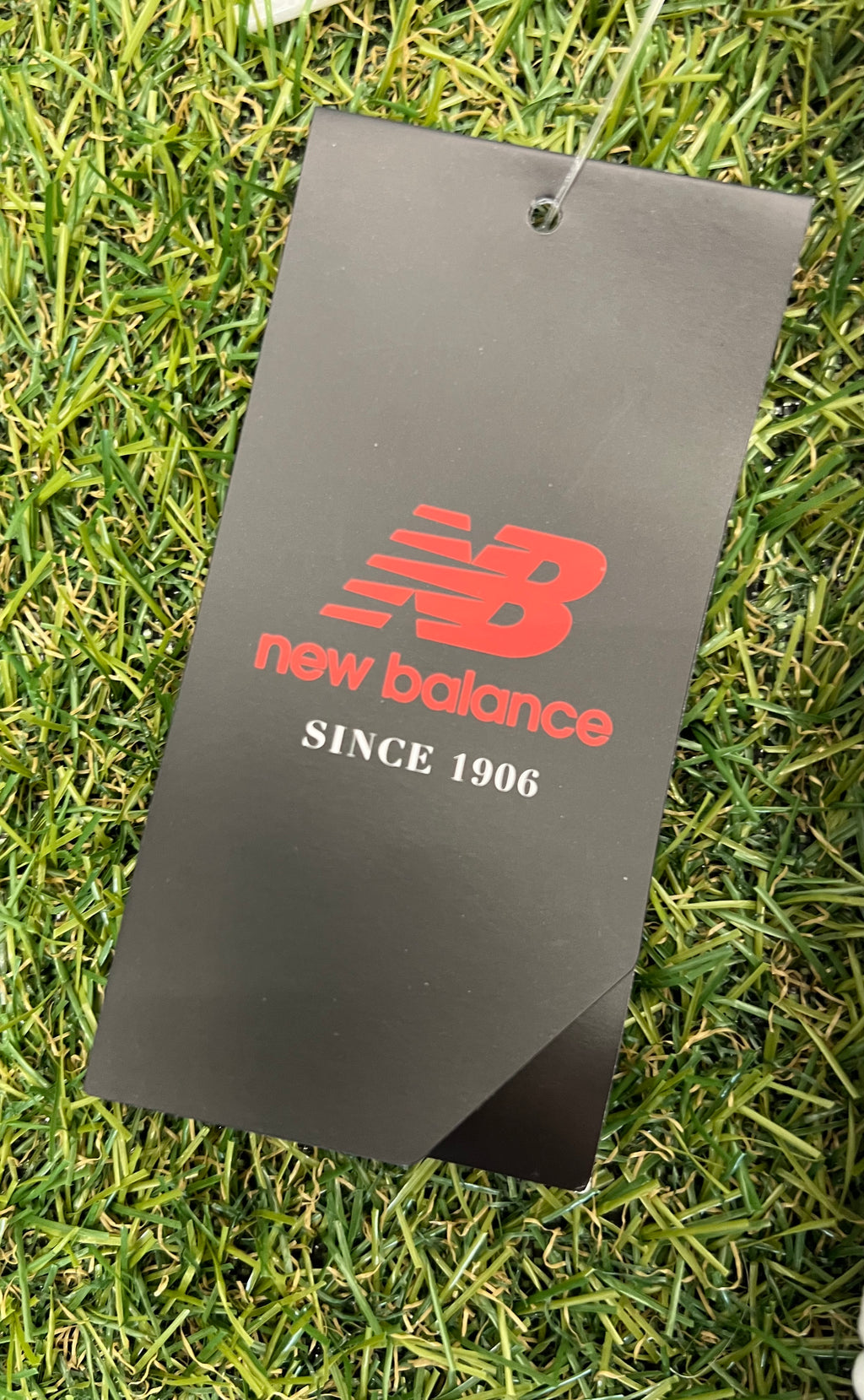 New Balance black and red branded product tag attached to cricket trousers