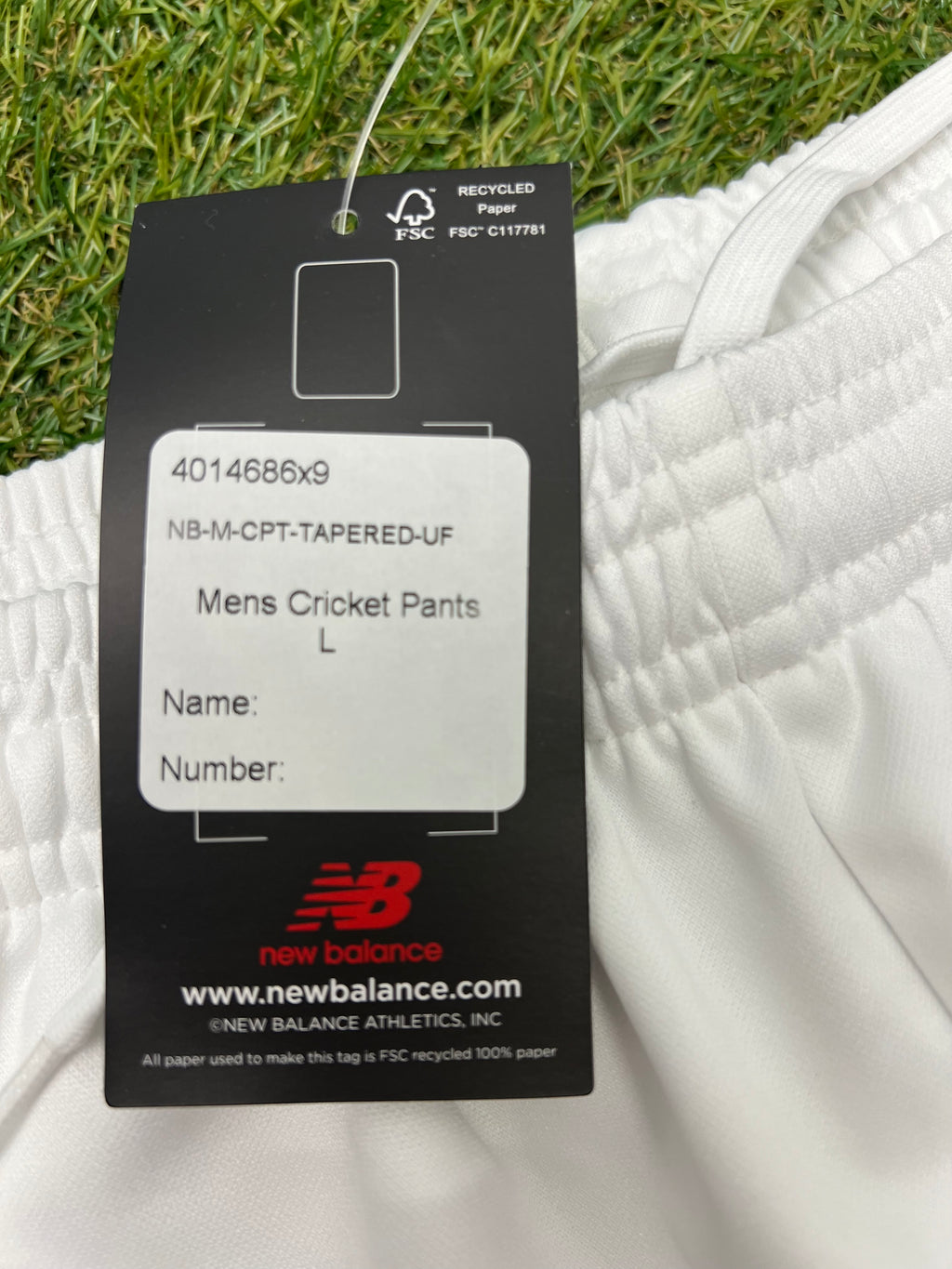 Close-up of product label on white cricket trousers showing size large and recycled paper tag