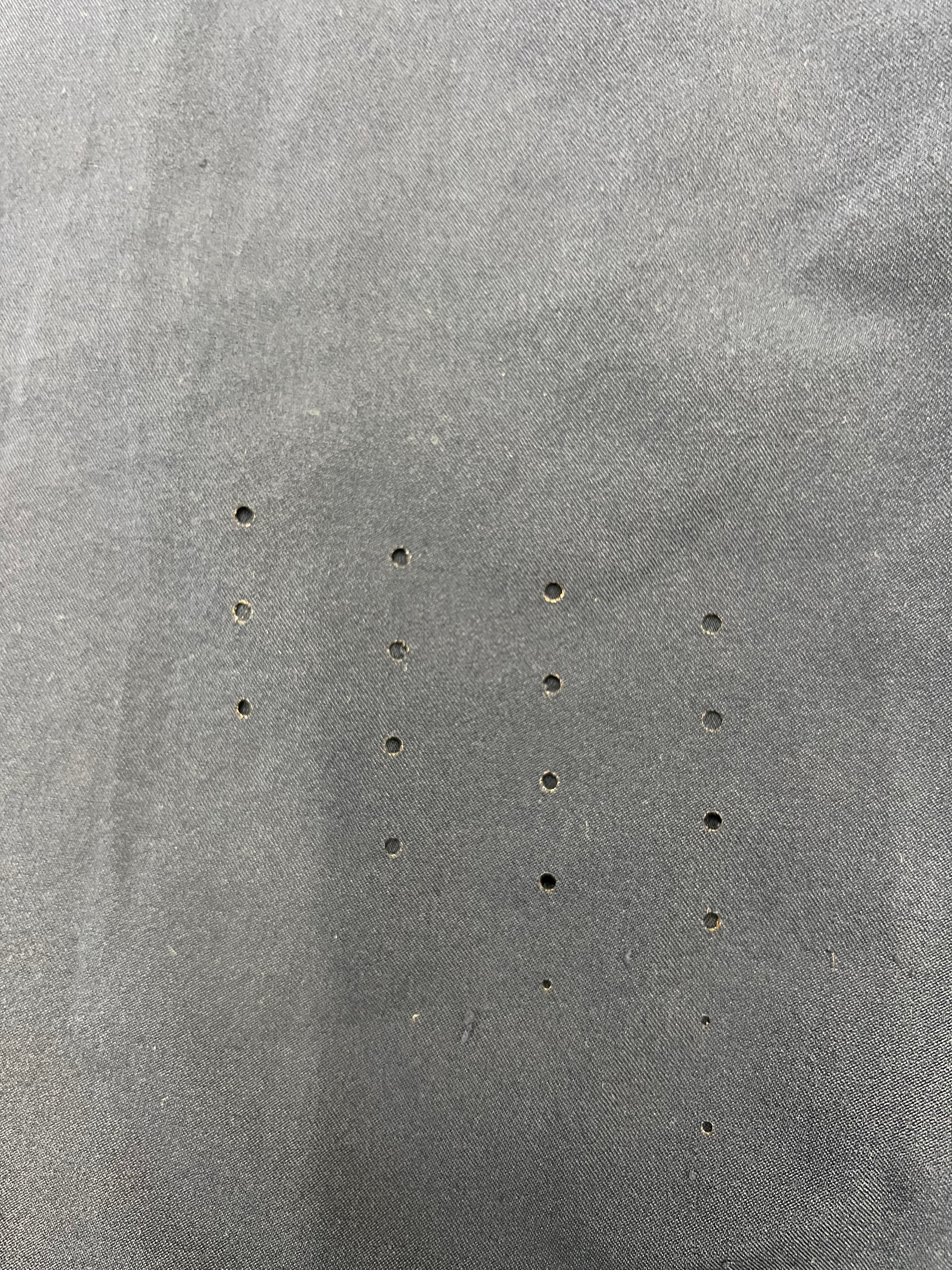 Close-up of small perforations on black tracksuit bottoms for ventilation