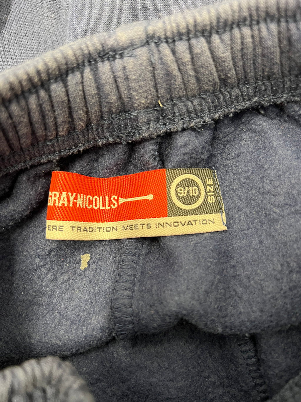 Close-up of Gray-Nicolls label inside elastic waistband of kids tracksuit bottoms showing size 9/10