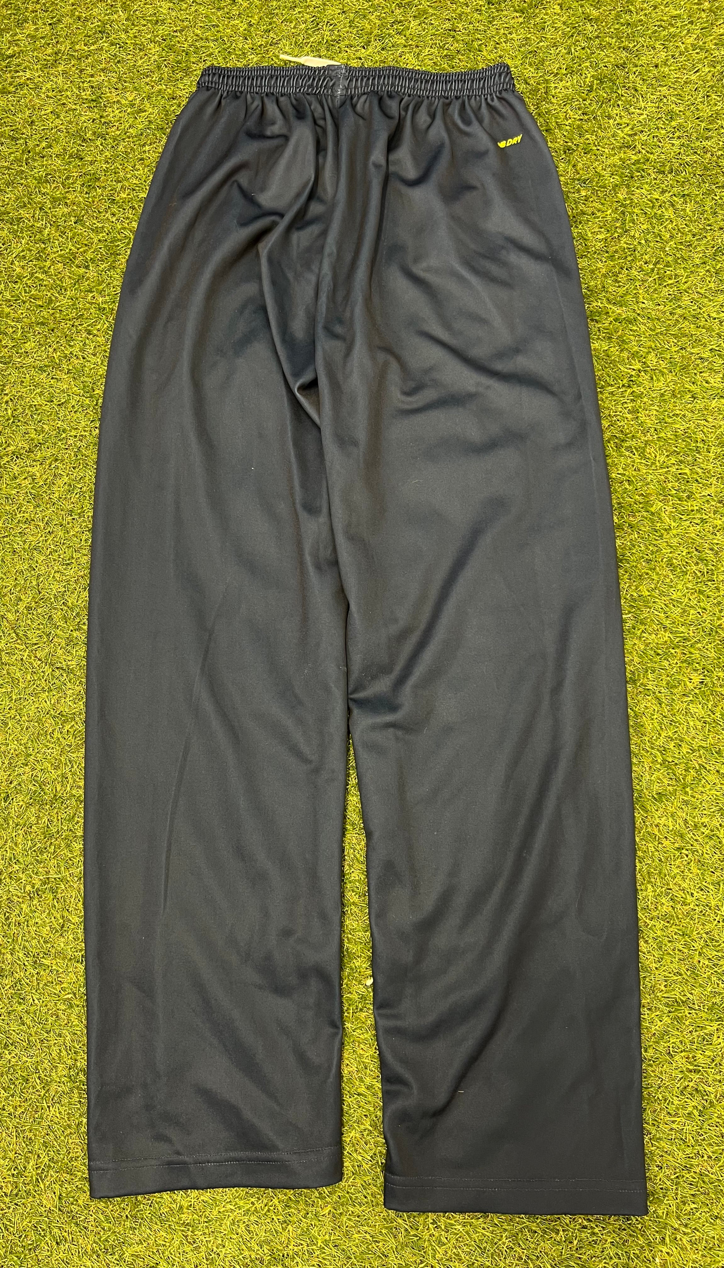 Back view of black New Balance cricket tracksuit bottoms showing elastic waistband and moisture-wicking dry fabric tag