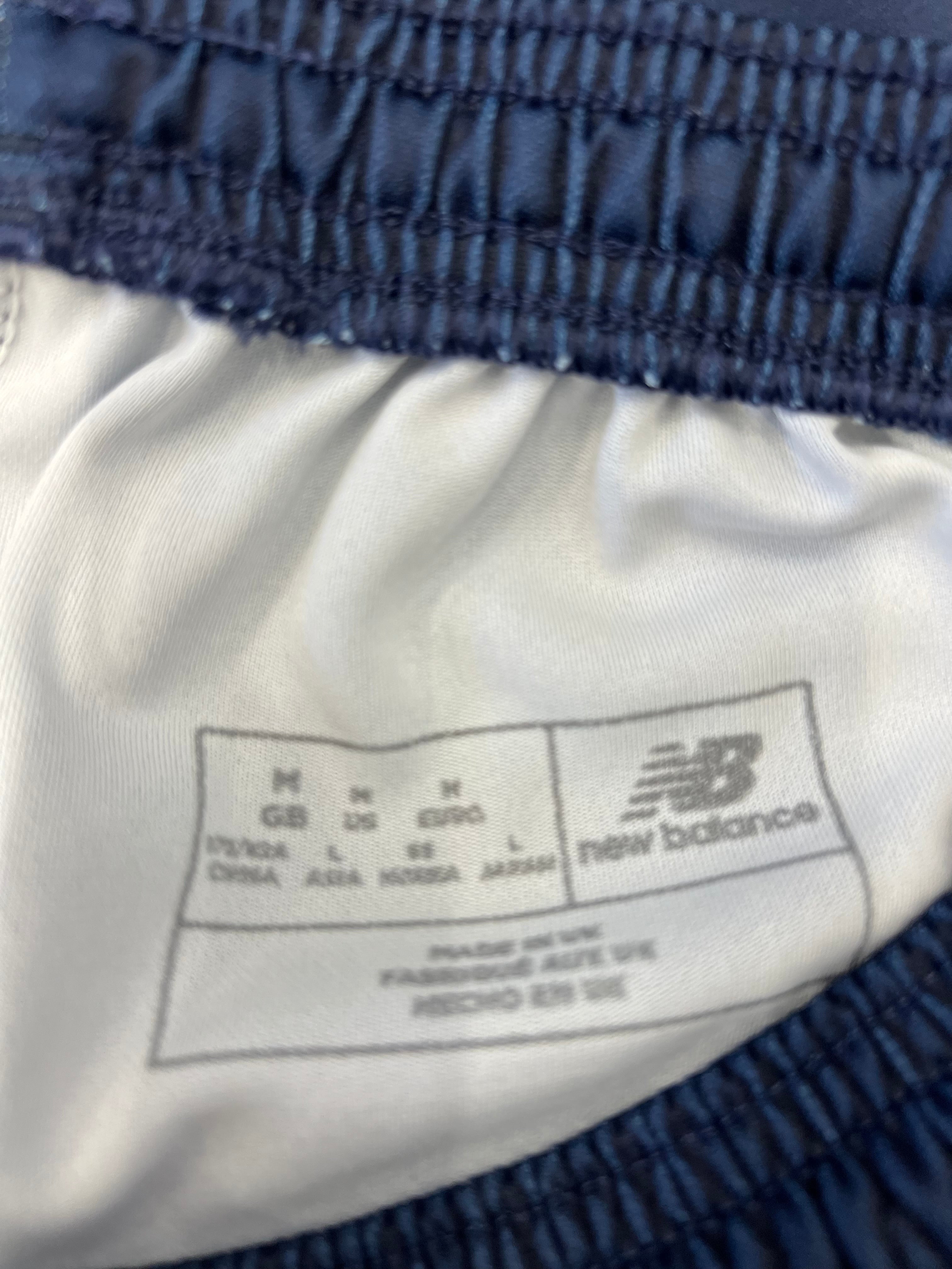 Close-up of New Balance size and care label inside black tracksuit bottoms