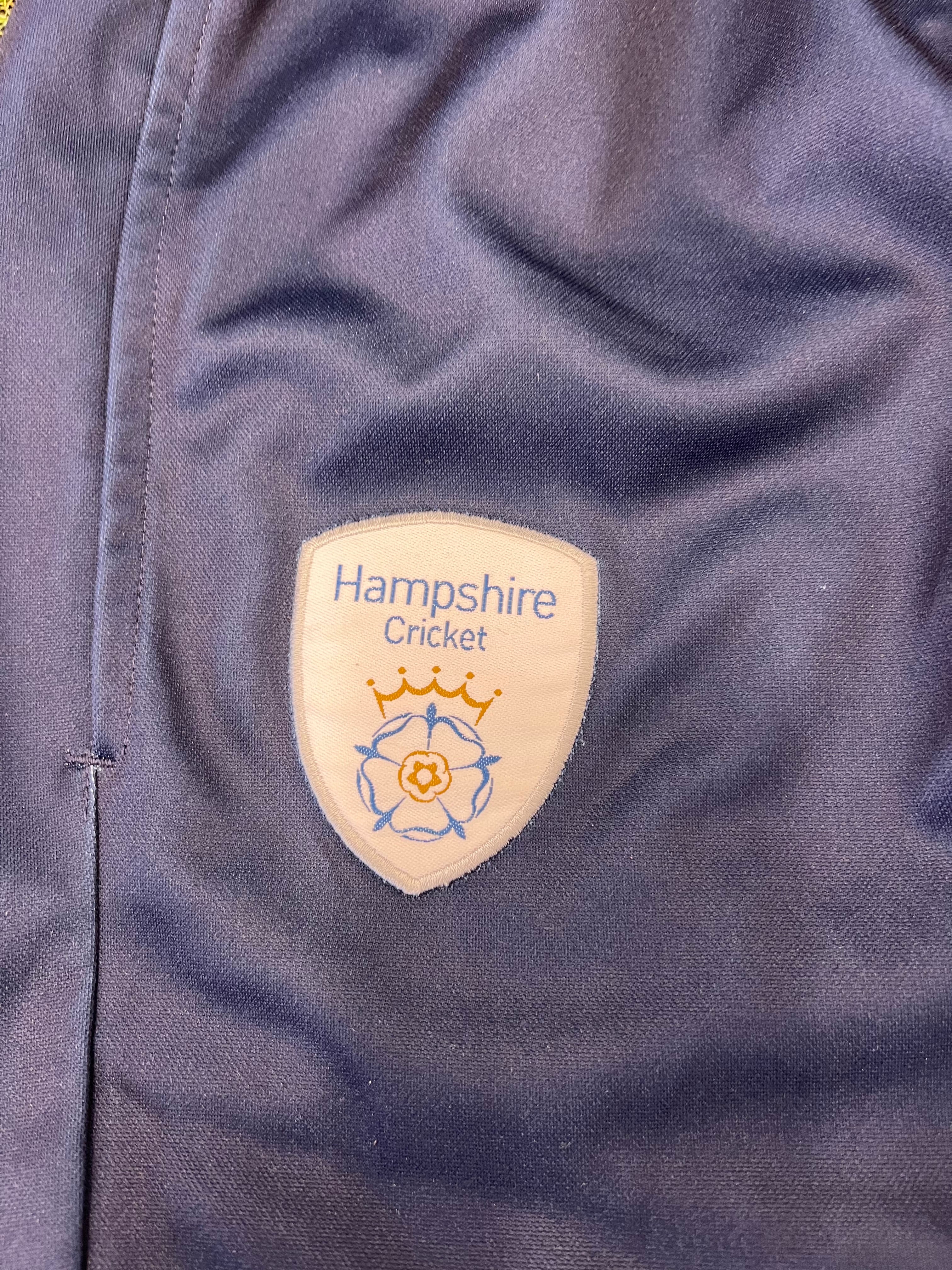 Detailed close-up of Hampshire Cricket emblem on black cricket tracksuit bottoms