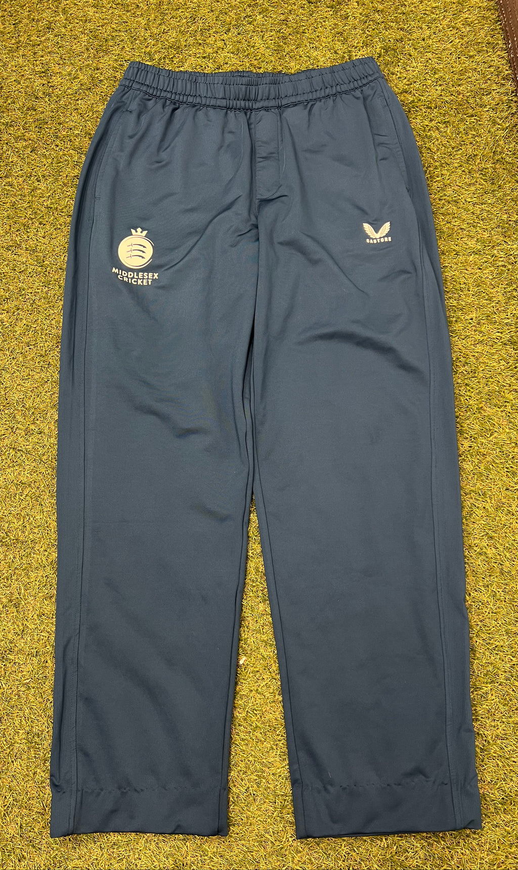 Front view of men's dark navy Castore Middlesex cricket tracksuit bottoms on grass