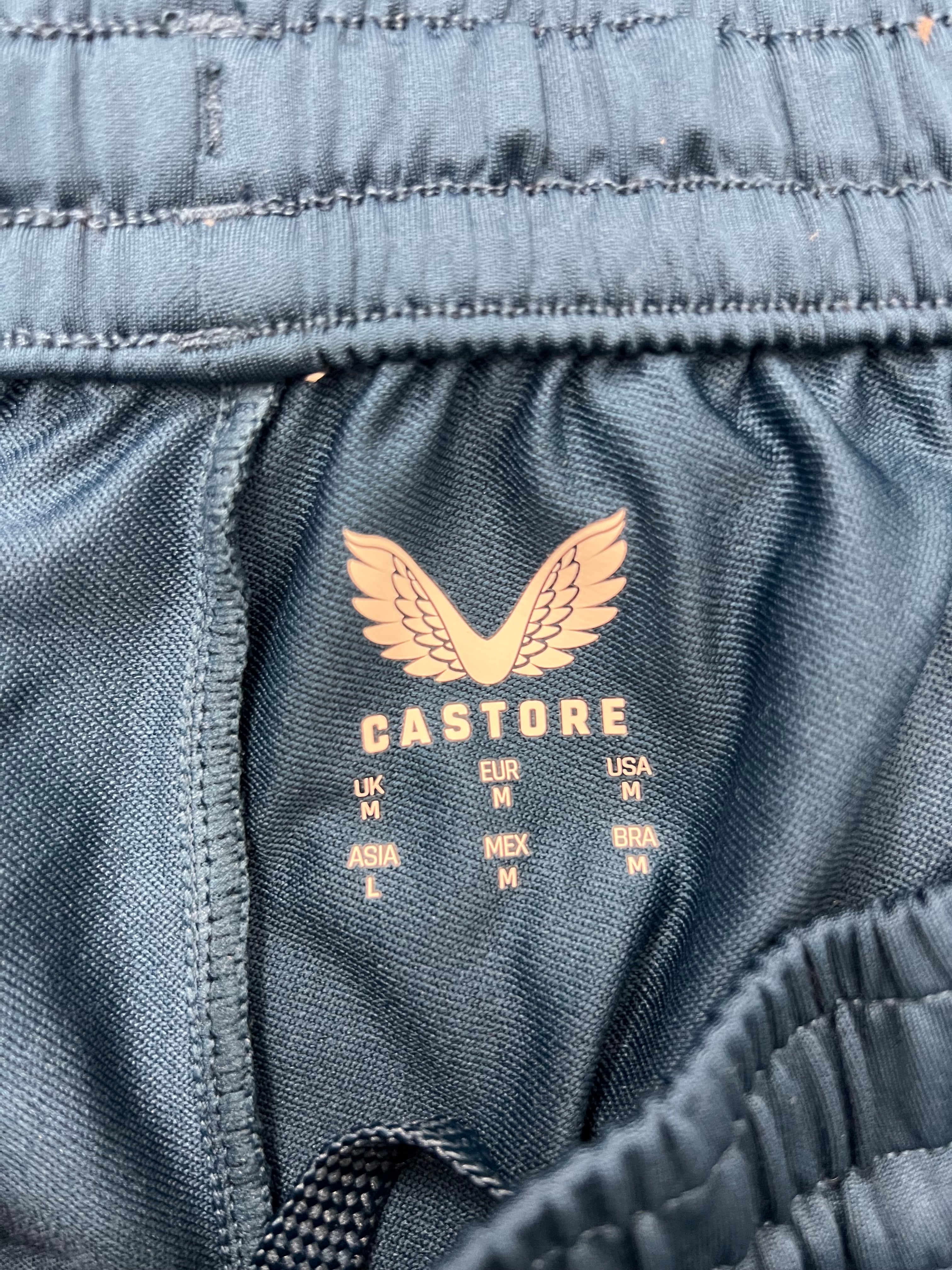 Close-up of inner elastic waistband label inside the dark navy Castore tracksuit bottoms showing size details