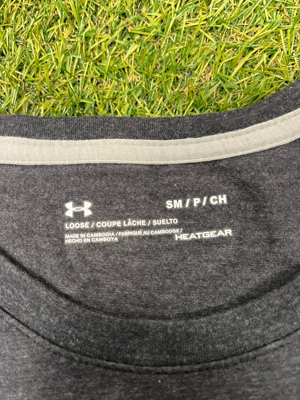 Close-up view of the collar label inside a grey Under Armour HeatGear t-shirt showing size small and loose fit details