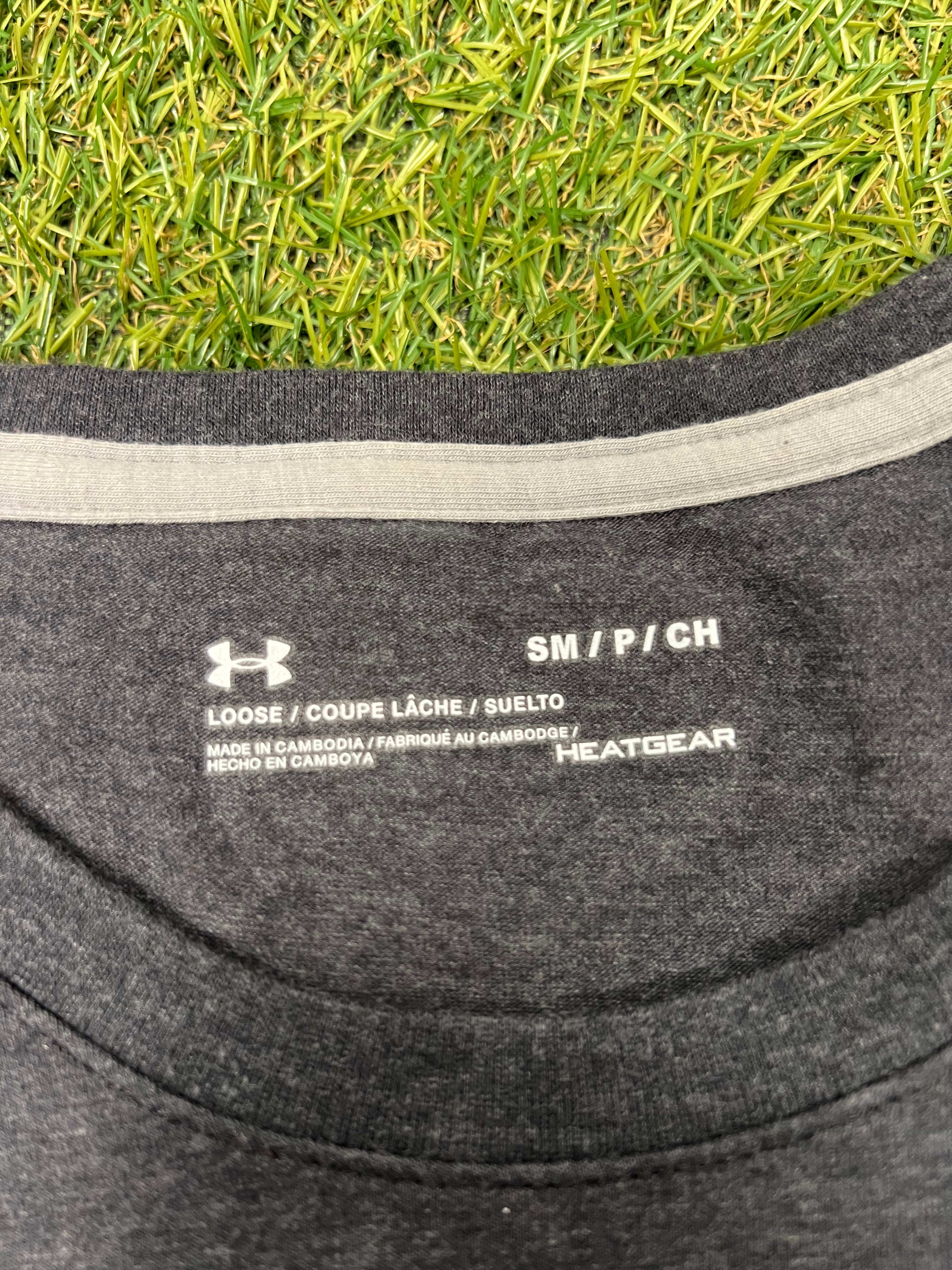 Close-up view of the collar label inside a grey Under Armour HeatGear t-shirt showing size small and loose fit details