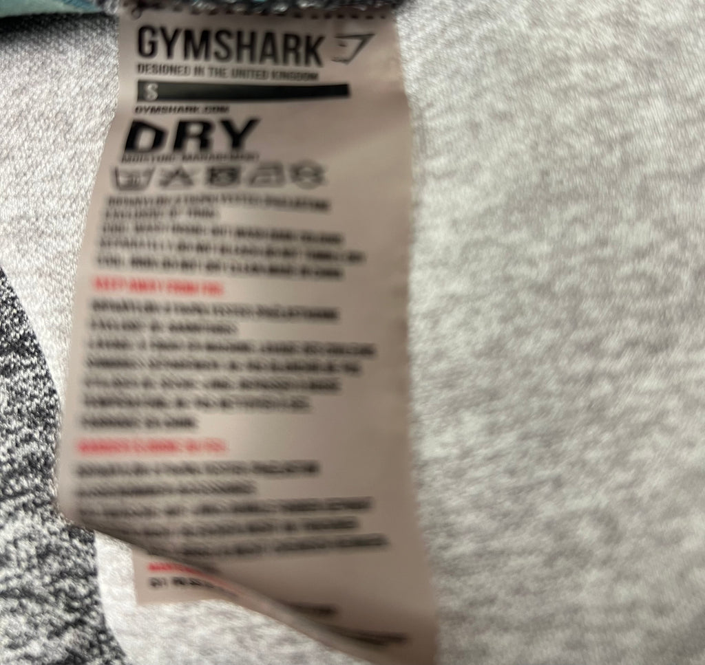 Close-up image of the Gymshark label on grey leggings highlighting moisture-wicking dry fabric technology