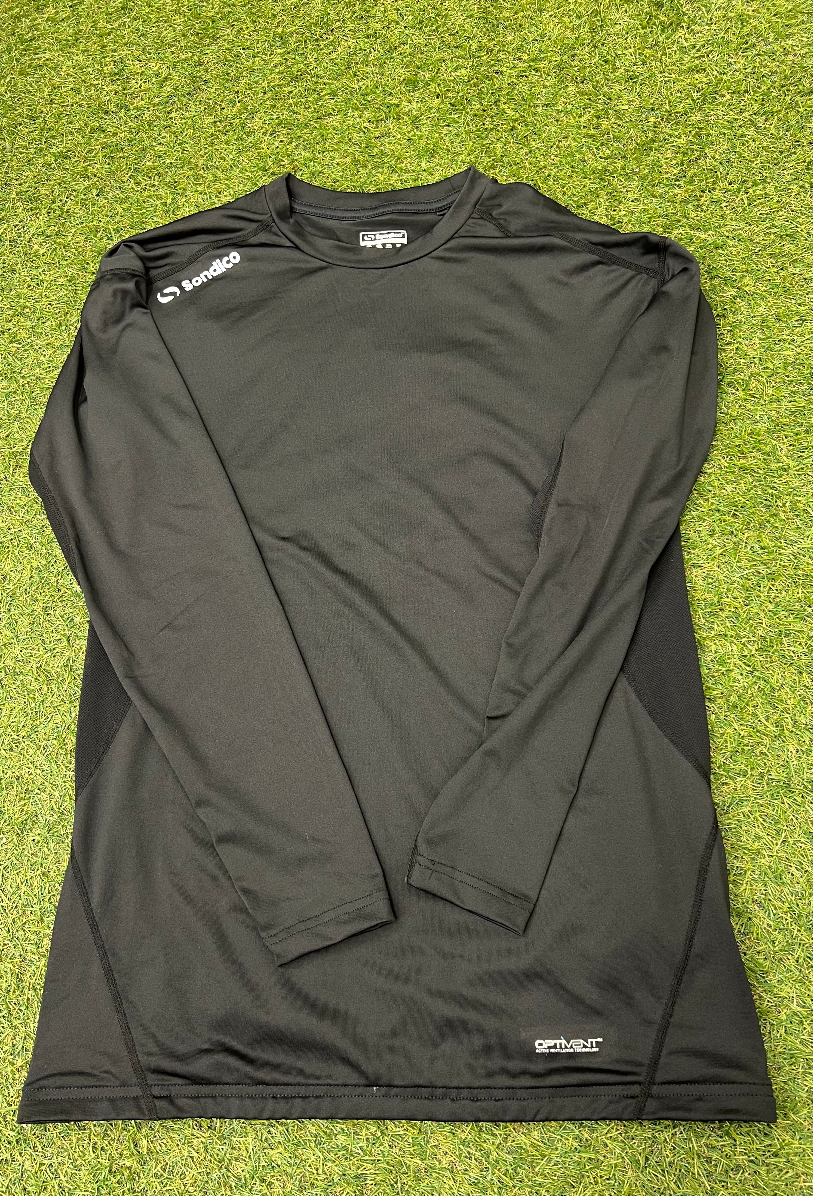 Front view of black Sondico men's long sleeve base layer top laid out flat on grass