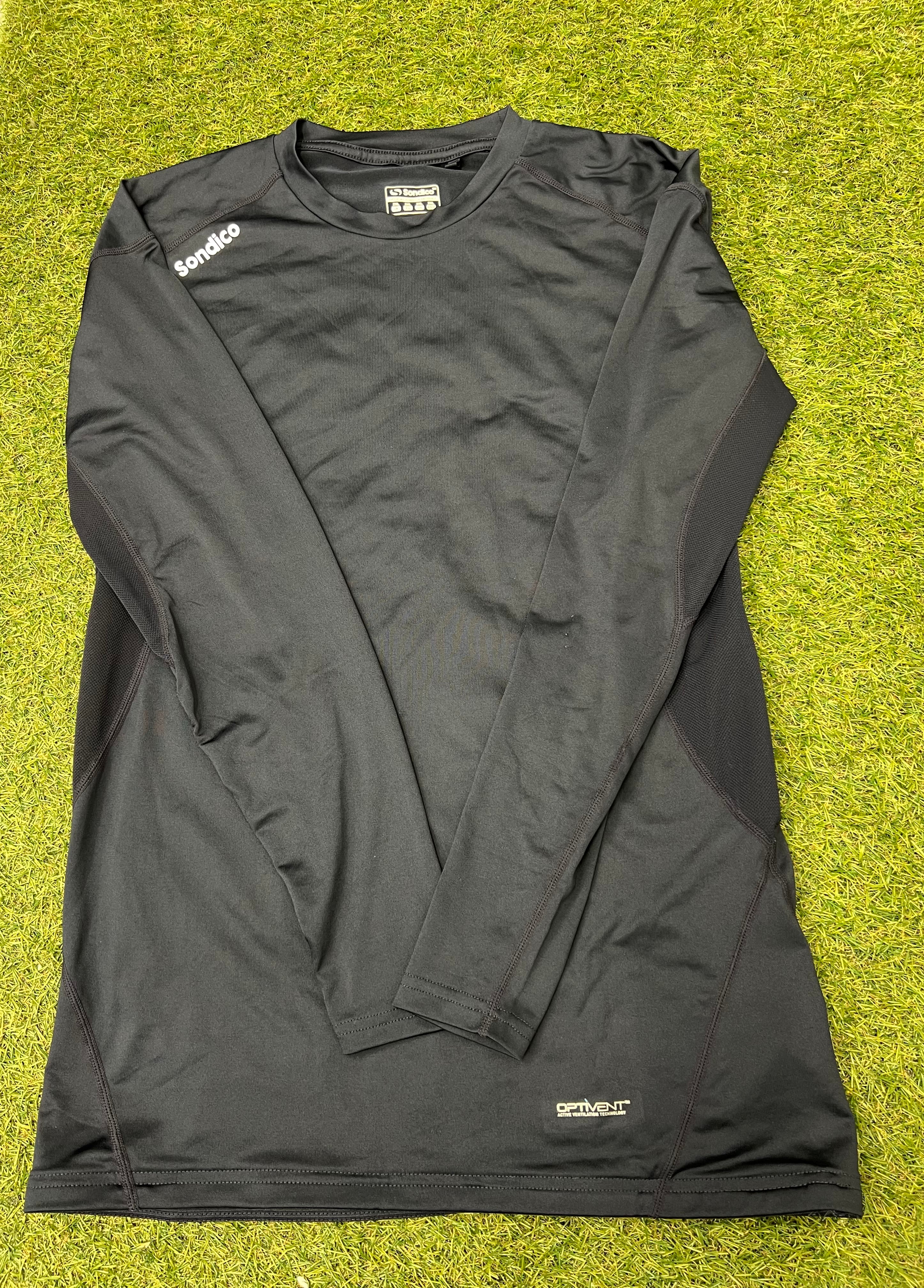 Front view of dark navy Sondico men's long sleeve base layer top laid out flat on grass
