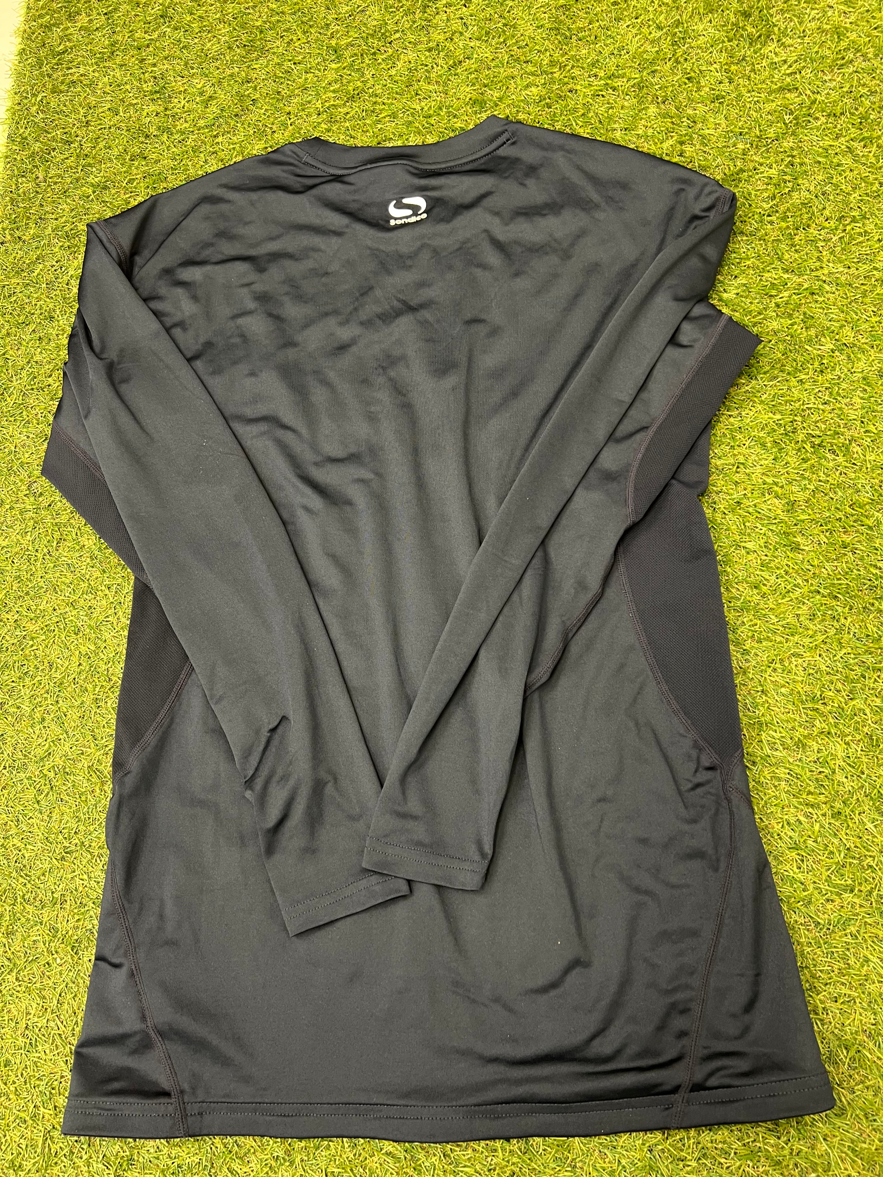 Back view of dark navy Sondico men's long sleeve base layer top laid out flat on grass