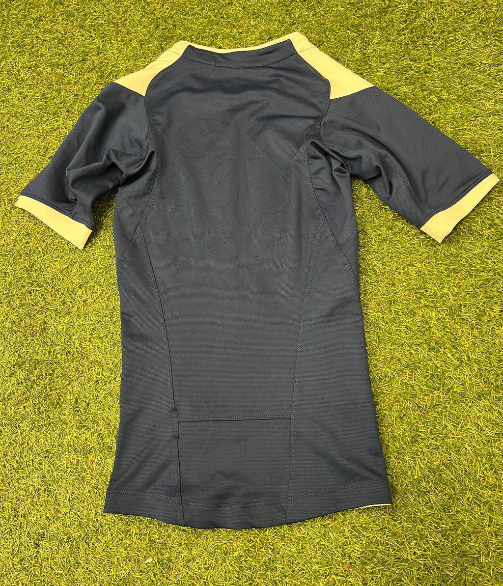 Back side of the black Nike FFR rugby jersey with cream collar and cuffs, laid flat on grass