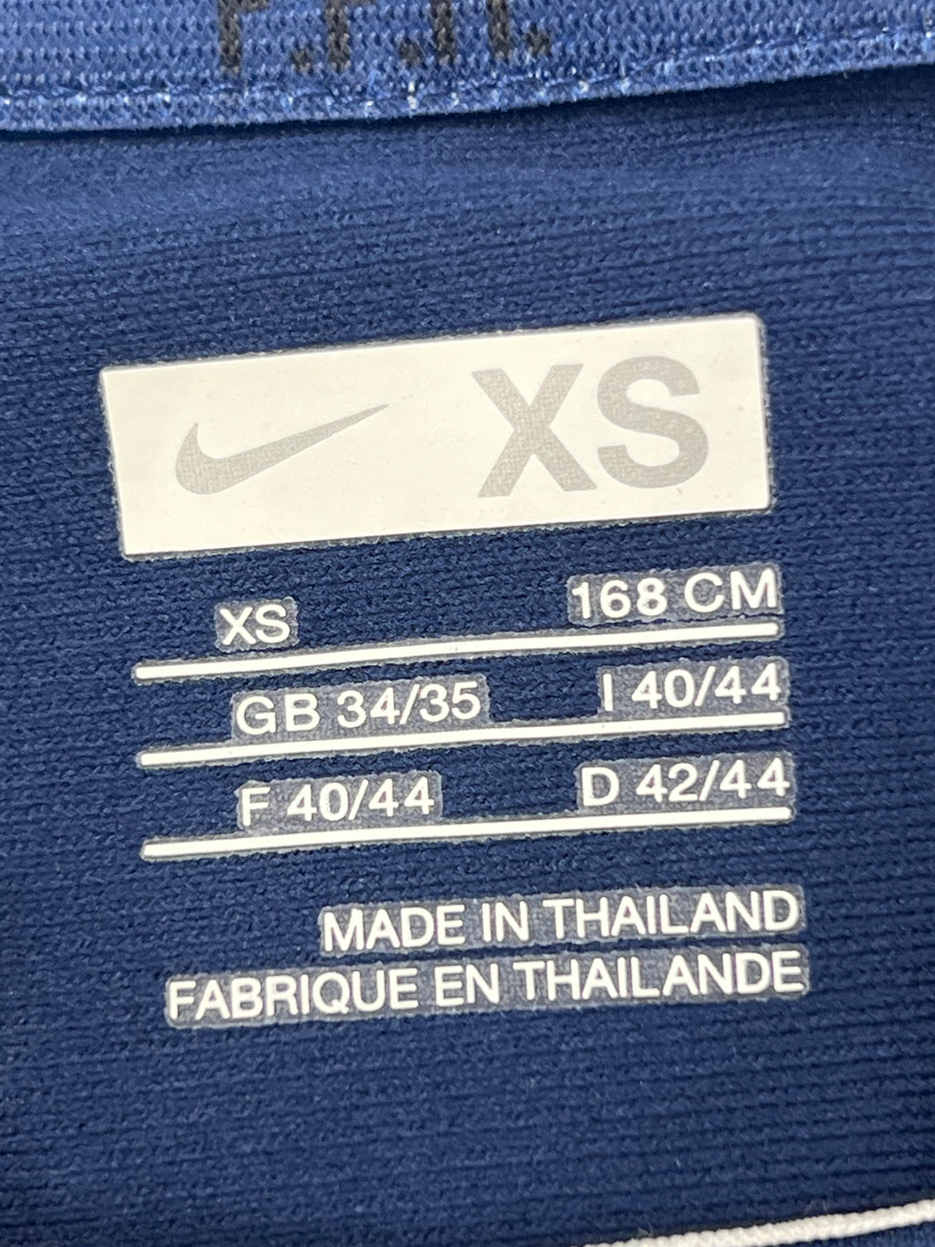 Close-up of the Nike branded size label marked XS with country sizing info, made in Thailand