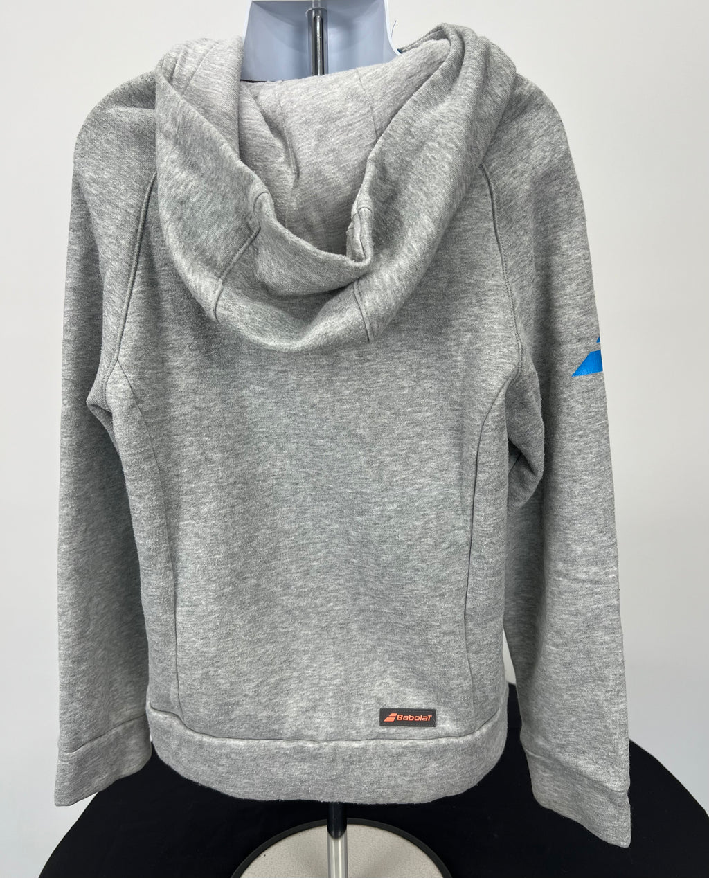 Back view of grey kids Babolat hoodie showing hood and small logo patch near waist