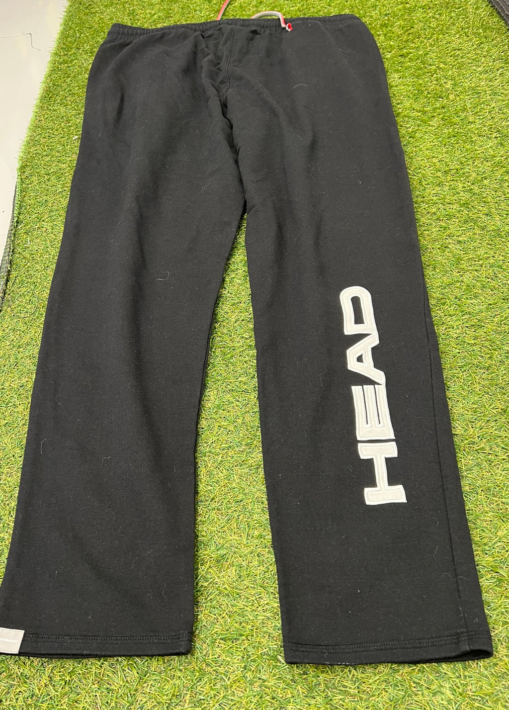 Back view of men’s black Head tracksuit bottoms displaying large vertical Head logo on left leg