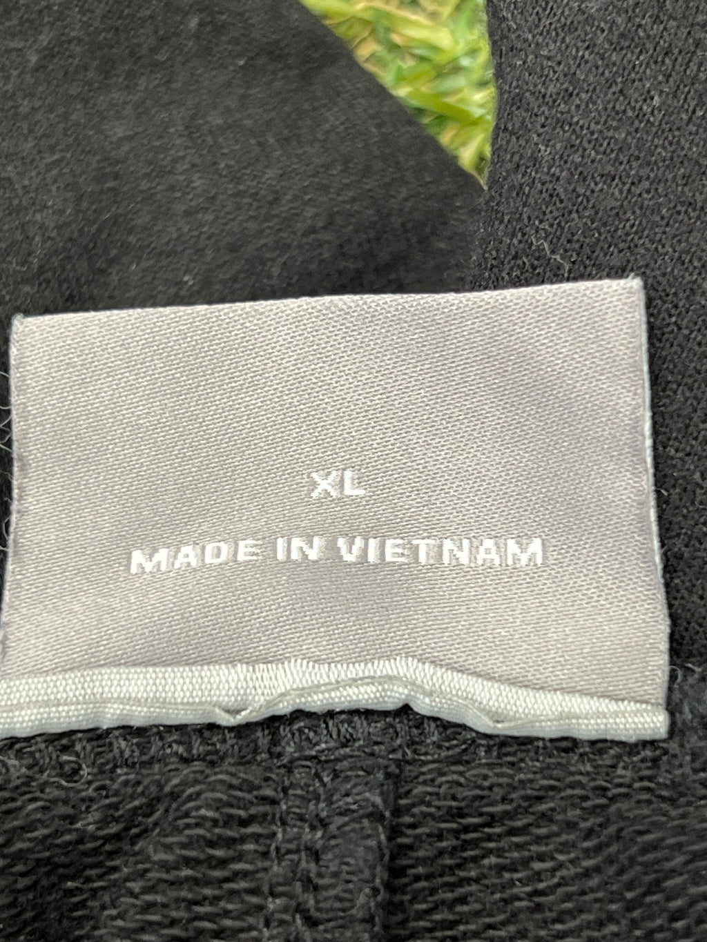 Close-up image of grey size label inside tracksuit bottoms showing XL and made in Vietnam text