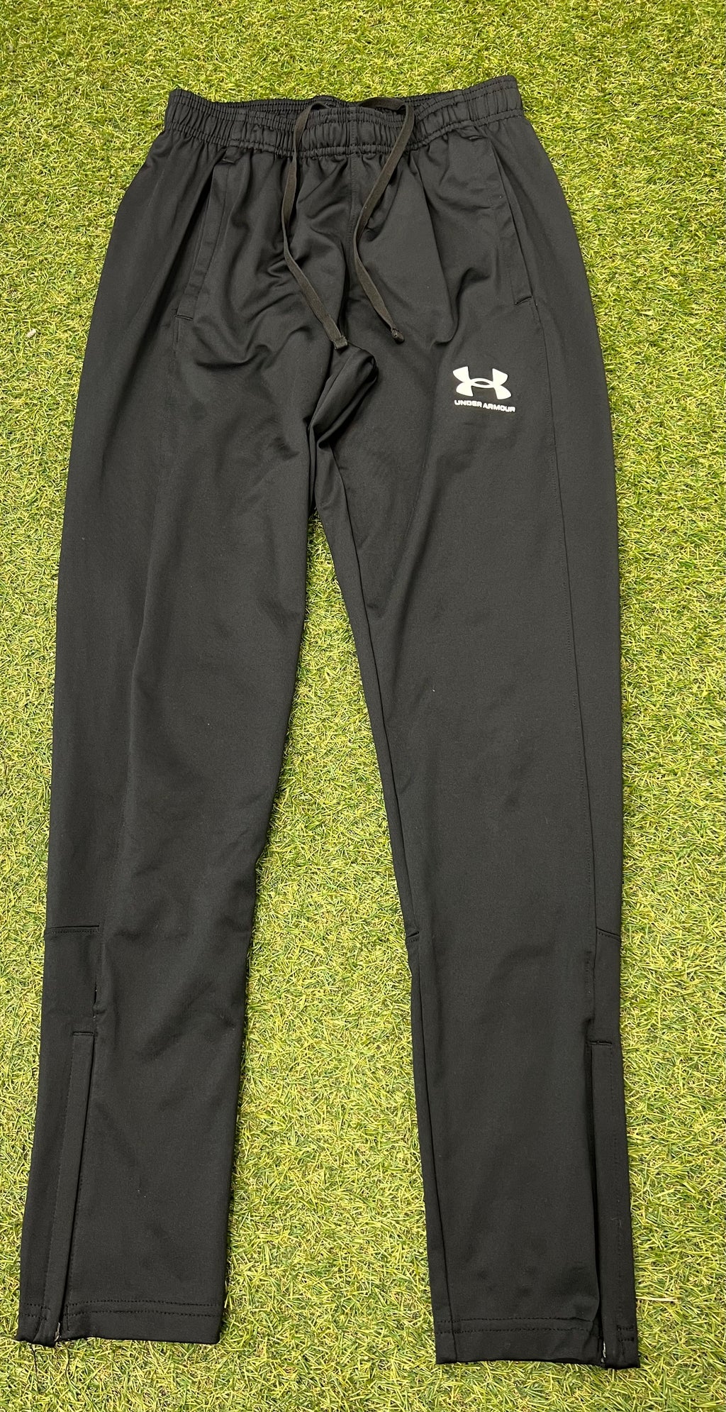 Close-up front view of black Under Armour tracksuit trousers with logo and drawstring waistband