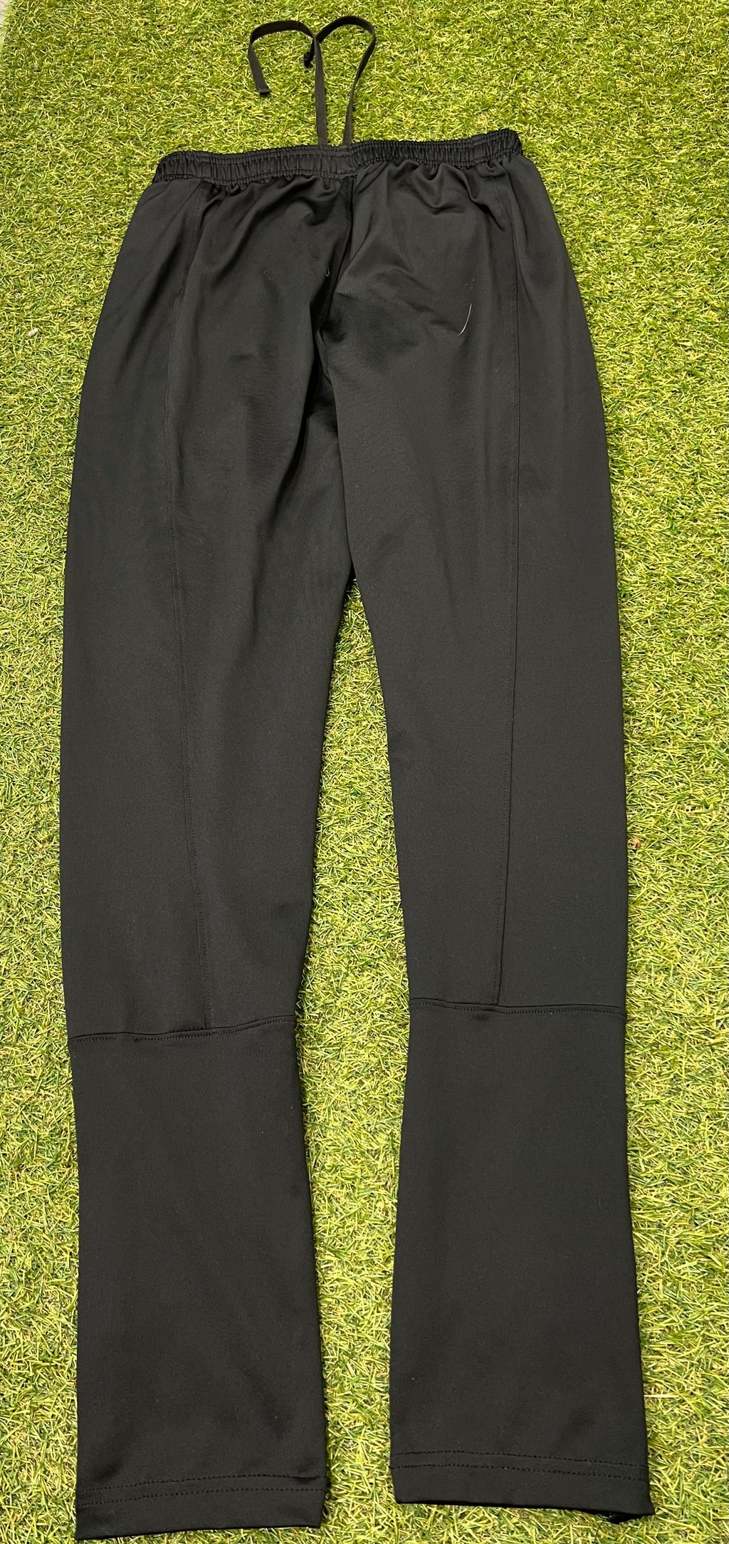 Close-up of black tracksuit trousers ankle showing zippered leg opening