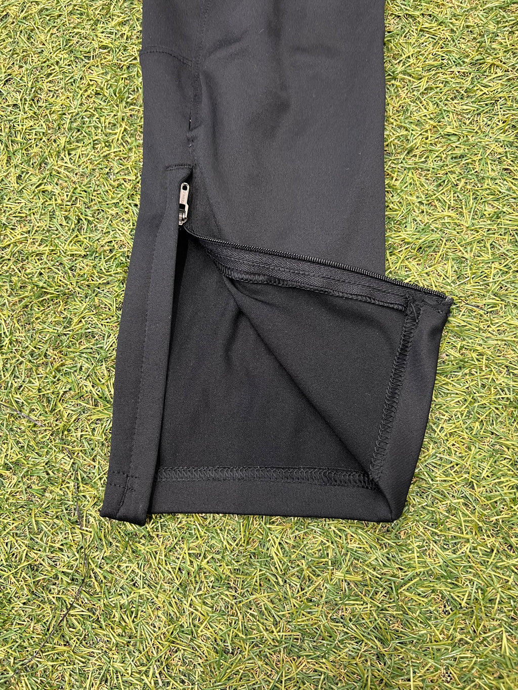 Inside waistband label of black Under Armour tracksuit trousers showing size small and fitted style