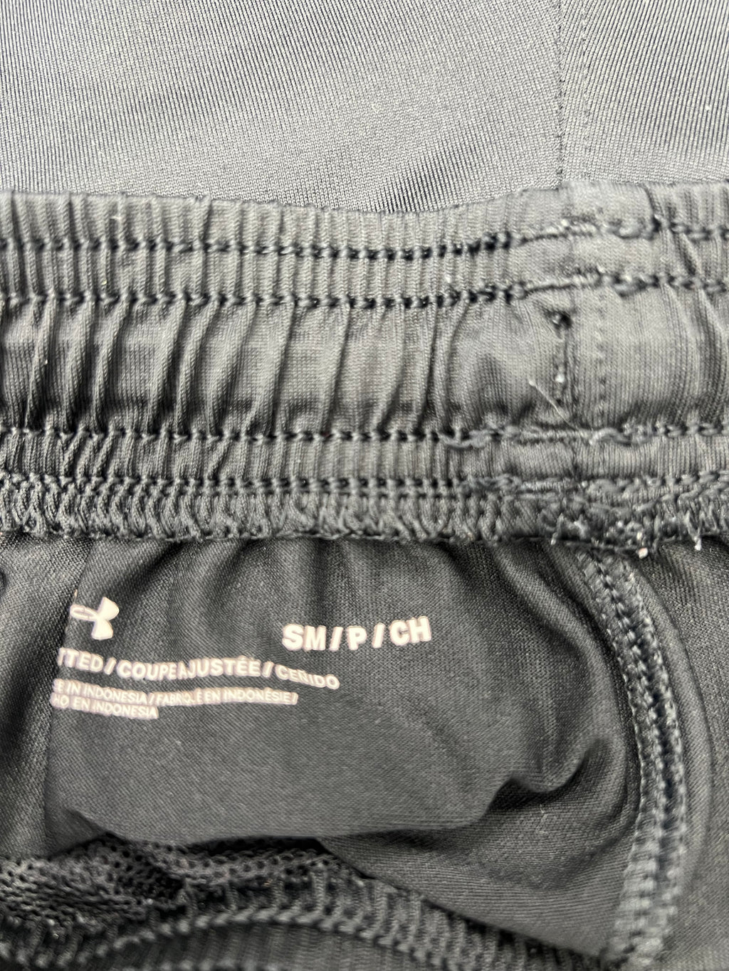 Front view of grey Under Armour tracksuit trousers with drawstring and logo on thigh