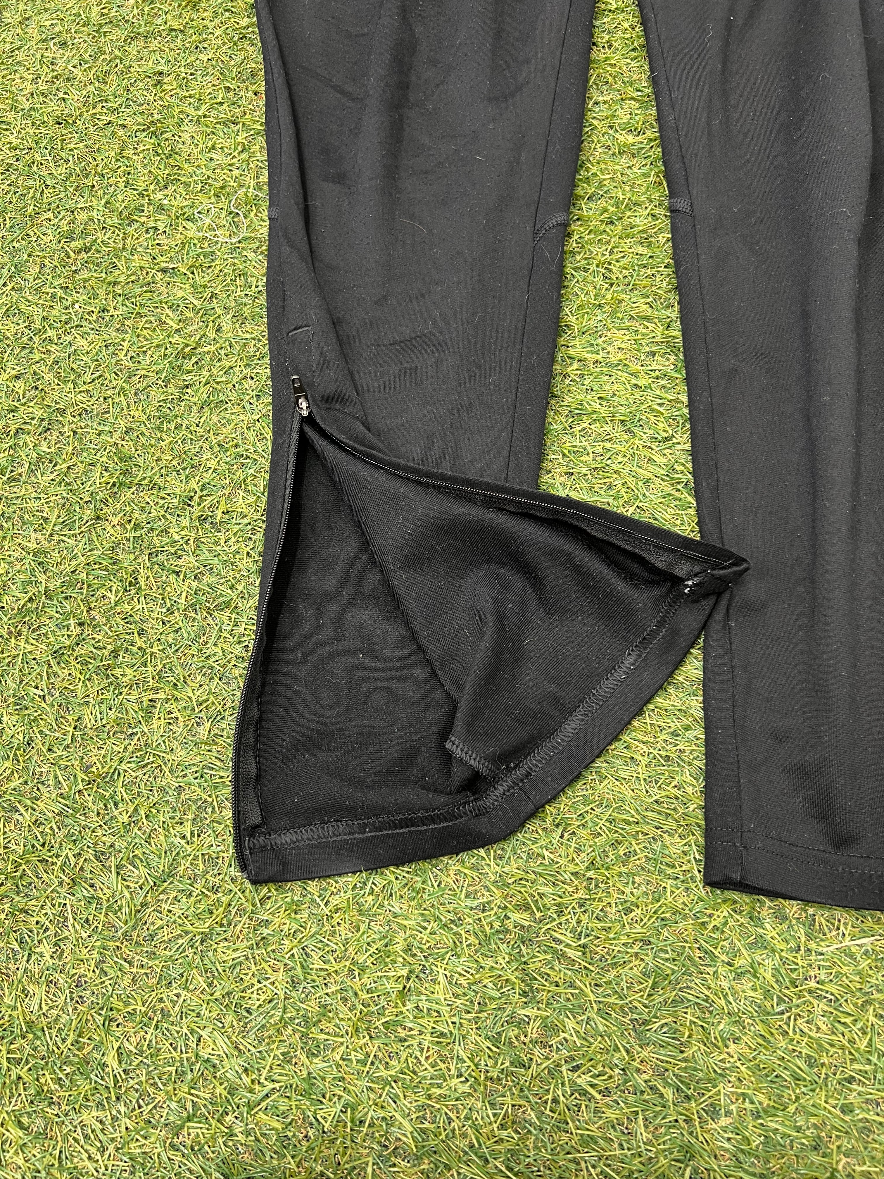 Close-up of the zipped leg opening detail on Nike black tracksuit bottoms