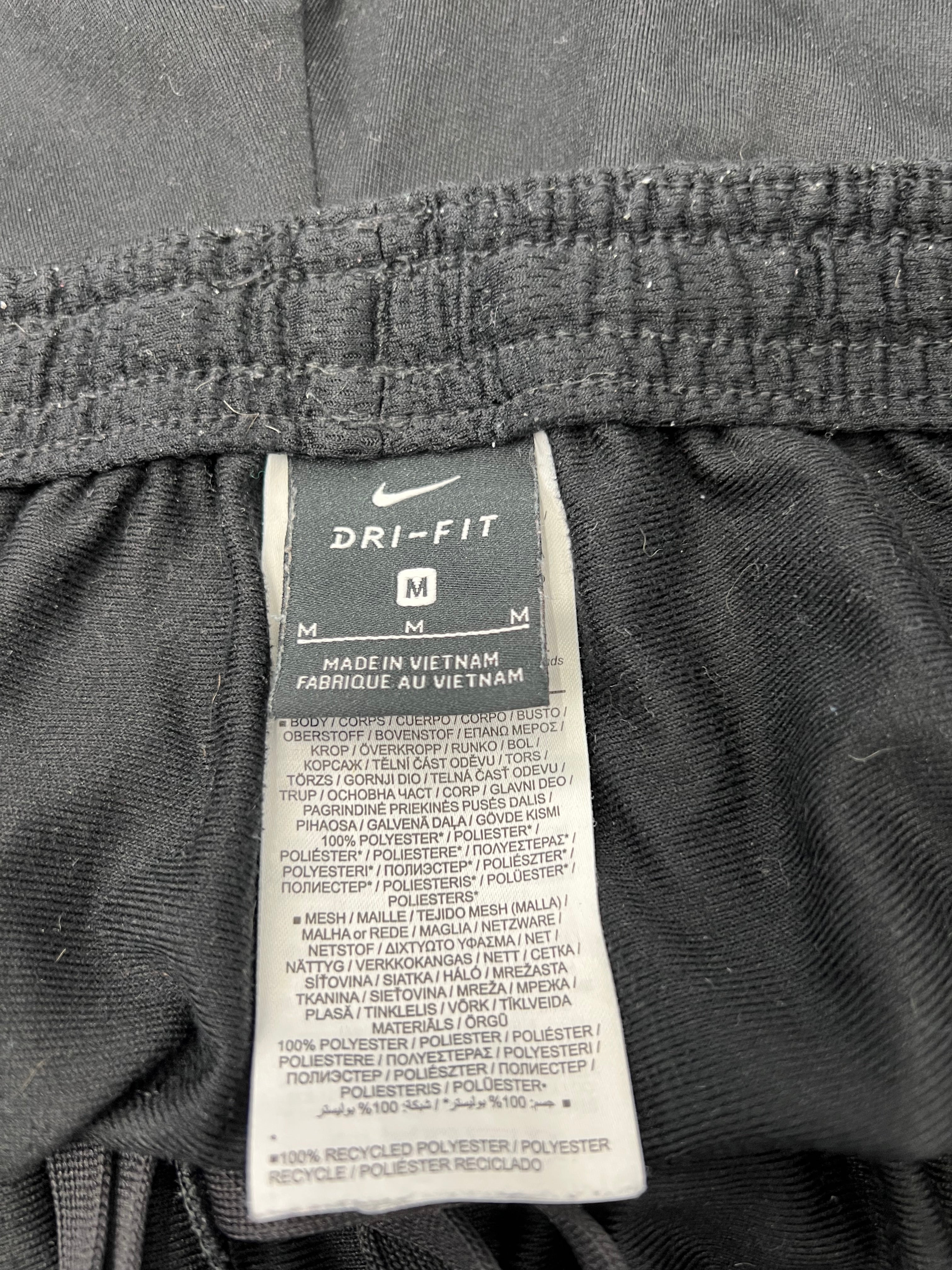 Label showing Nike Dri-FIT size M and fabric composition of polyester