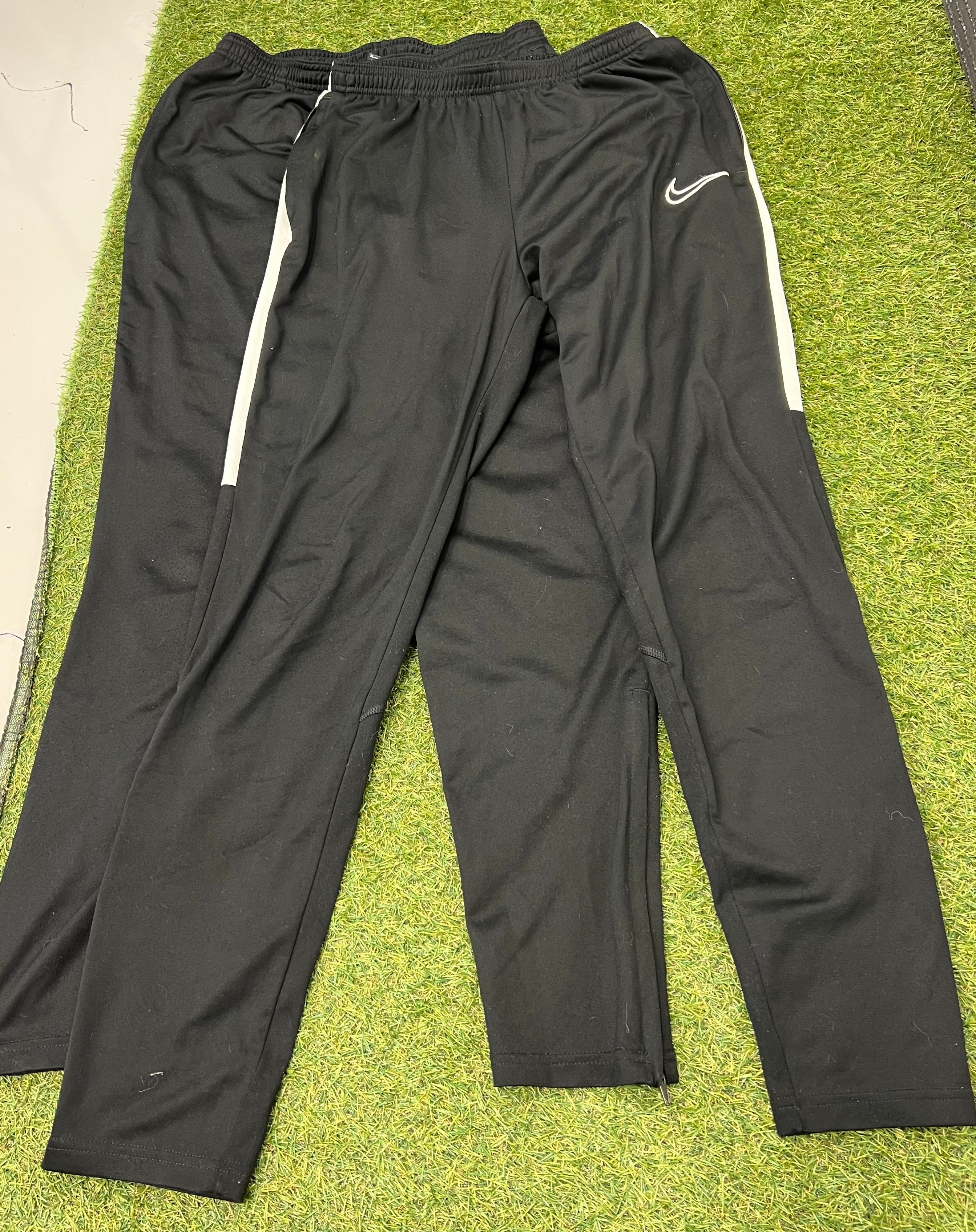 Pair of Nike black tracksuit bottoms with elastic waist and side zippered legs on grass